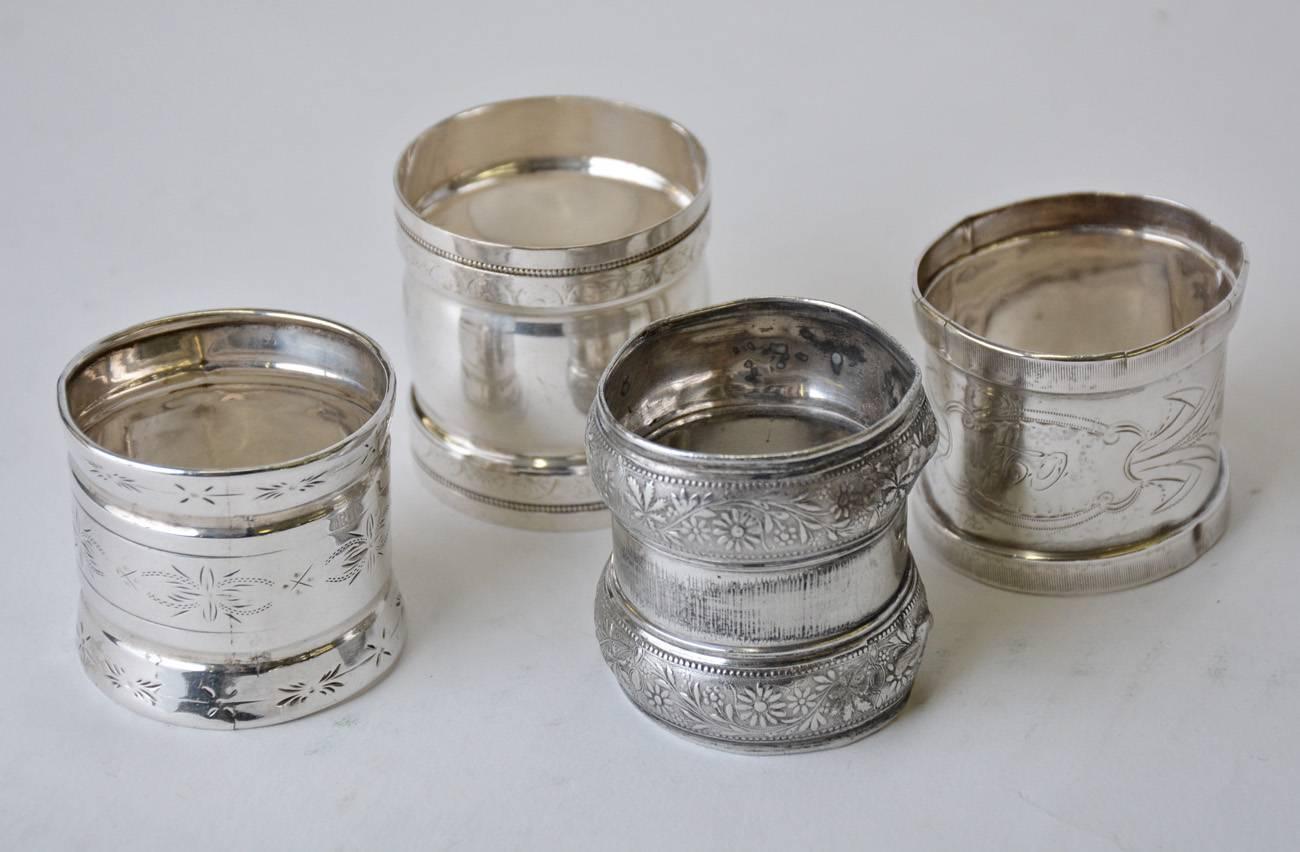 Collection of four late Victorian silver napkin rings with four different styes.
1. Has flared edges, three bands of leaves and a monogram. Measures: 37