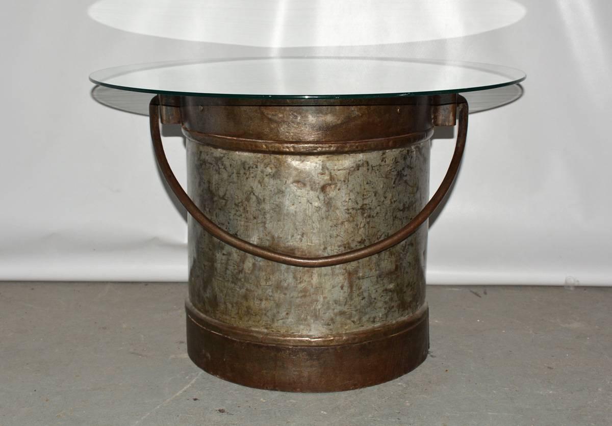 The antique two-toned iron bucket with handle has been transformed into a coffee table with the addition of a round glass top. Glass is for photo purposes only. Two matching buckets are available. Buckets can be used for multiple purposes -- logs