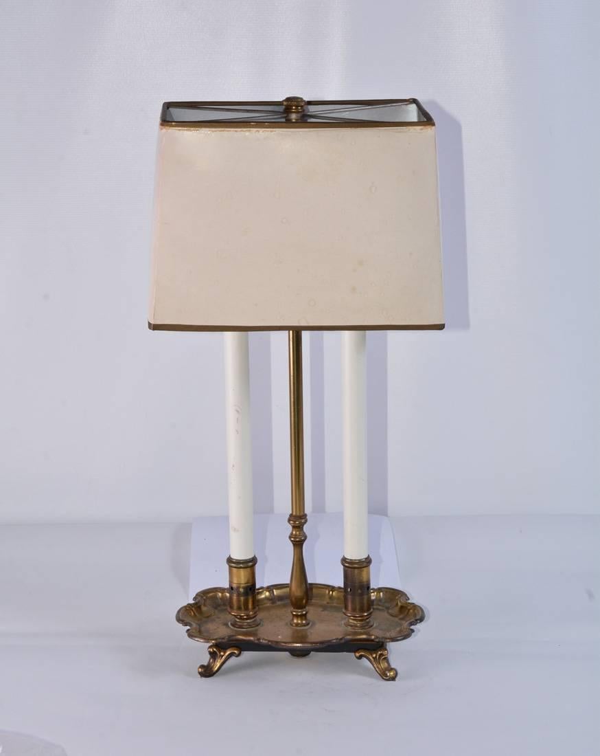 The vintage brass bouillette table or desk lamp is in the Rococo style and has a two-light electrical socket wired for US use. The lamp has the effect of two candlesticks and a brass centre pole to hold the wiring to the double socket. The switch is