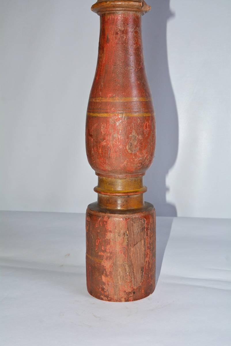 The table lamp is composed of an antique wood spindle painted red with yellow trim. The lamp has a single socket wired for US use. The shade is of taupe Belgium linen with a white plastic liner. The switch is attached to the electric