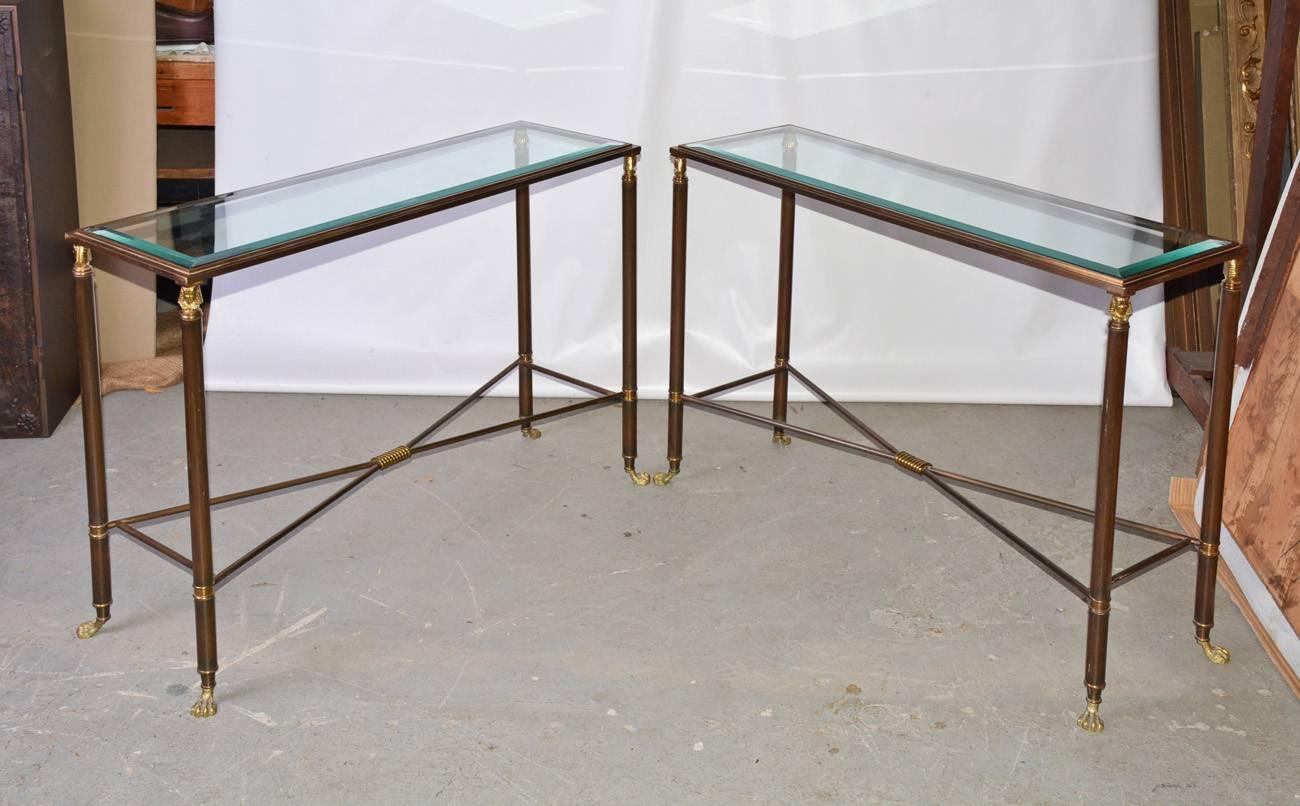 Pair of bronzed brass and glass top console or sofa tables having X-form stretchers and brass. Egyptian heads at the tops of the legs and paws at the bottom. The glass is set into the surrounding frames.
Can be sold singly.