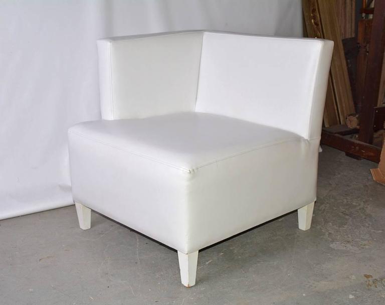 The contemporary single arm corner club chair is upholstered in white leather and the tapered wood legs are painted white.