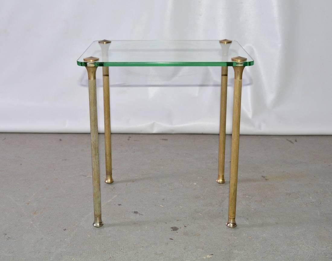 The petite midcentury Hollywood Regency style side table has fluted brass legs attached to a glass top. Wonderful to use as an occasional drink table, easily movable.