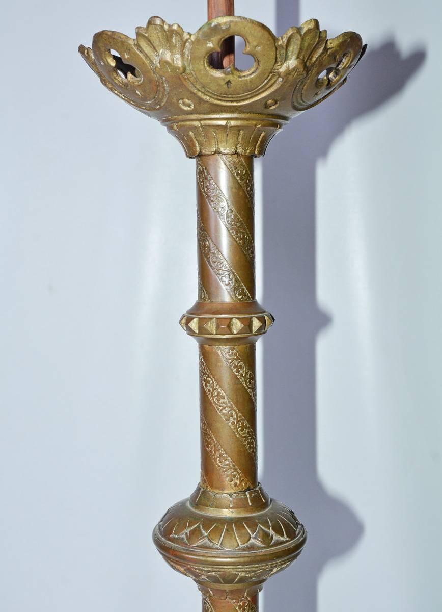 The pair of Gothic-style lamps are made of brass and are decorated with swirls of vines and leaves, as well as lion heads for feet.
Dimensions:  Brass decorative part -- 28