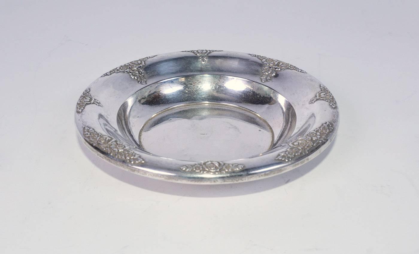 The mid-20th century bon bon candy dish has a border of roses and leaves en relief. Stamped 