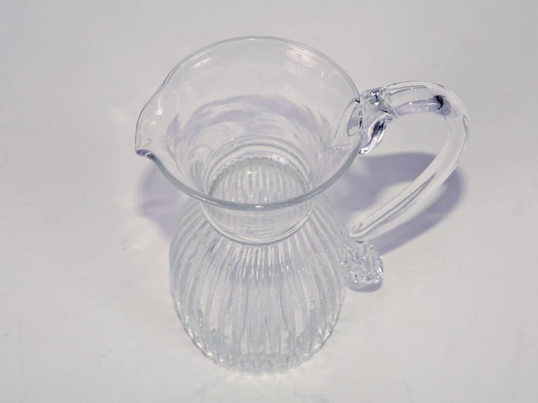 The small creamer pitcher is made of handblown clear glass and is stamped 
