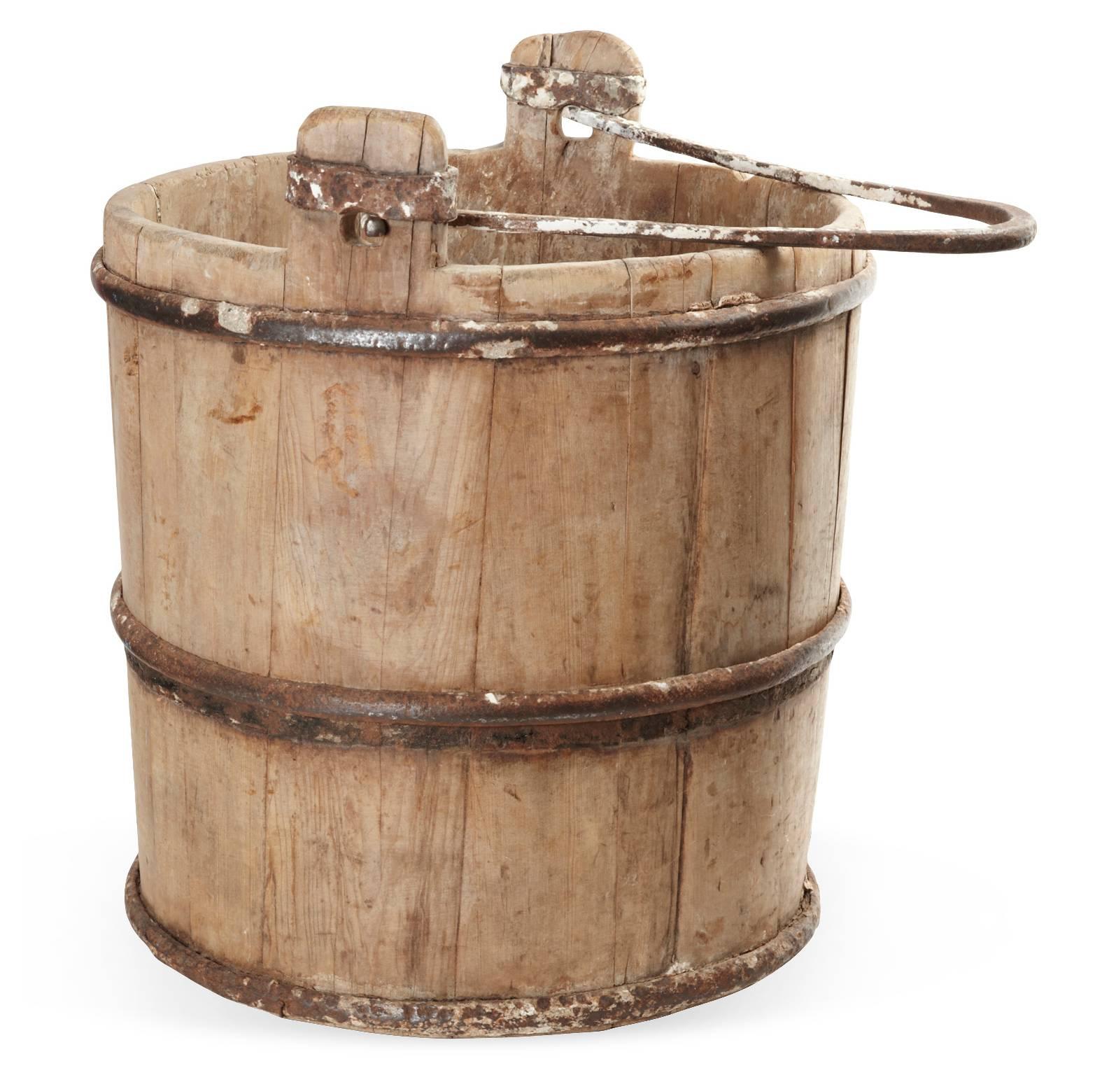 A classically shaped antique Chinese cypress water bucket with original cast iron handles and straps with lovely old wood patina. The rustic country style bucket has many practical uses including -- firewood/kindling storage, magazine or book