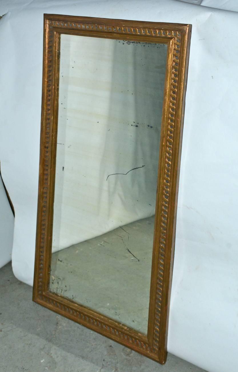 The long Victorian giltwood mirror has an inner border of the classical twisting guiloche design. The mirror has a wood backing and is wired for hanging.