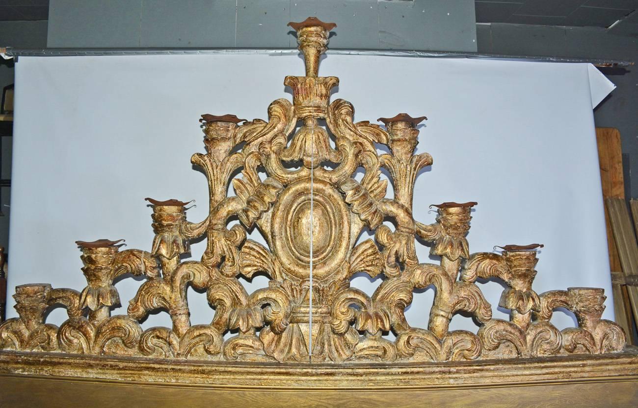 The antique Venetian pediment is made of hand-carved giltwood with a red undercoat. The elaborate carving is of equal rounded depth on both sides and could have topped a screen of some sort. The decorations include a centred bell flower, ovals,