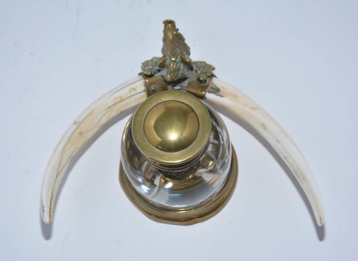 Antique English brass and crystal inkwell with small horns and brass boar head.
Diameter for bottle: 2.38