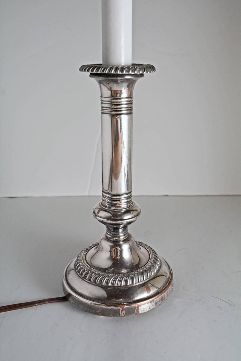 Slim and elegant, the pair of early 19th century English silver-on-copper candlesticks have been electrified for modern flame bulbs. The lamps have been weighted at the bottom and have ball feet. The striped fabric shades in black and tan have black