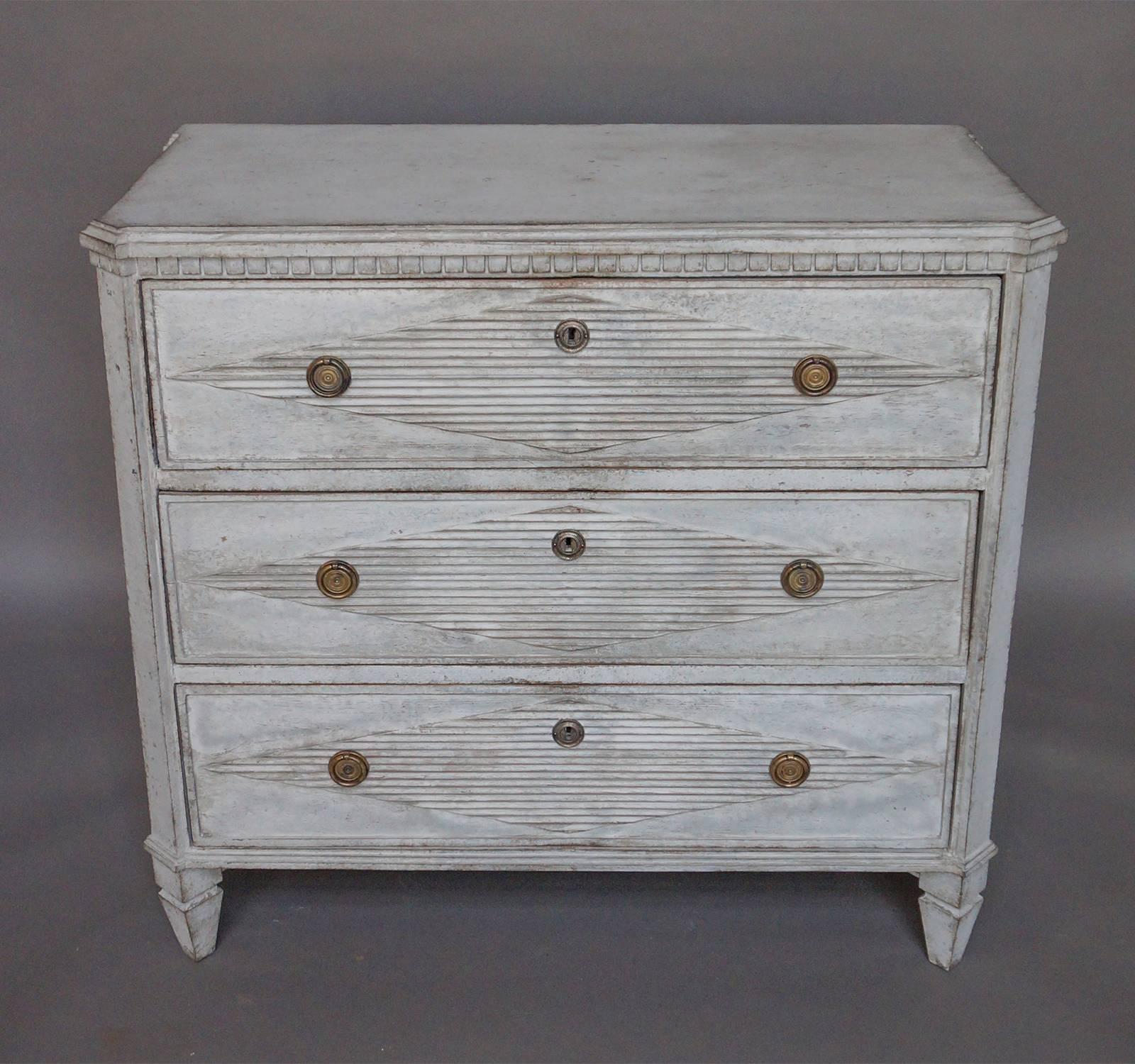 Swedish chest of drawers in the Gustavian Style, circa 1850. Three drawers, each with a raised and reeded lozenge and brass hardware. Shaped top, dentil molding and canted corners.