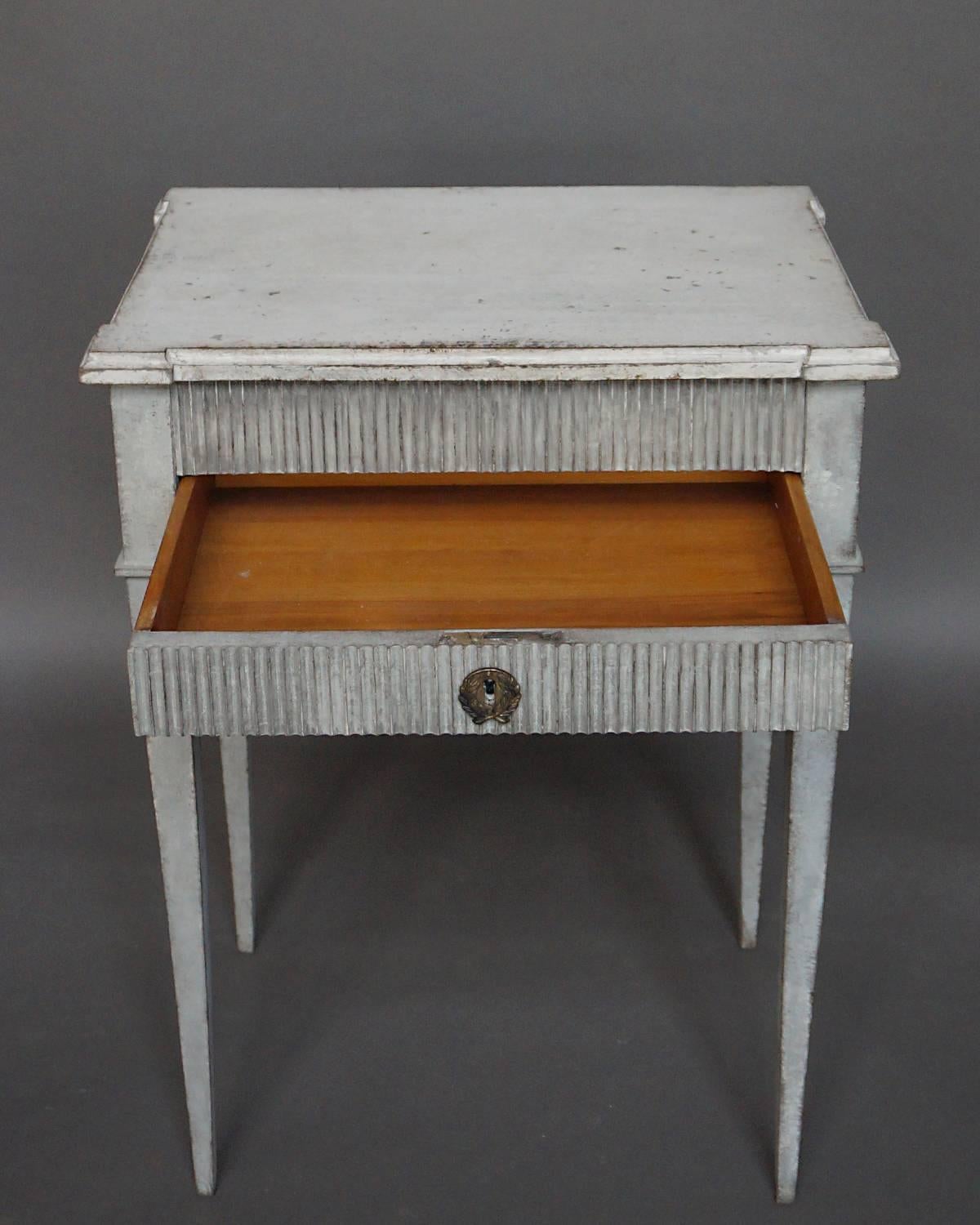 Small side table in the Gustavian Style, Sweden circa 1890, with shaped top, reeded front, and apron drawer. Simple tapering legs.