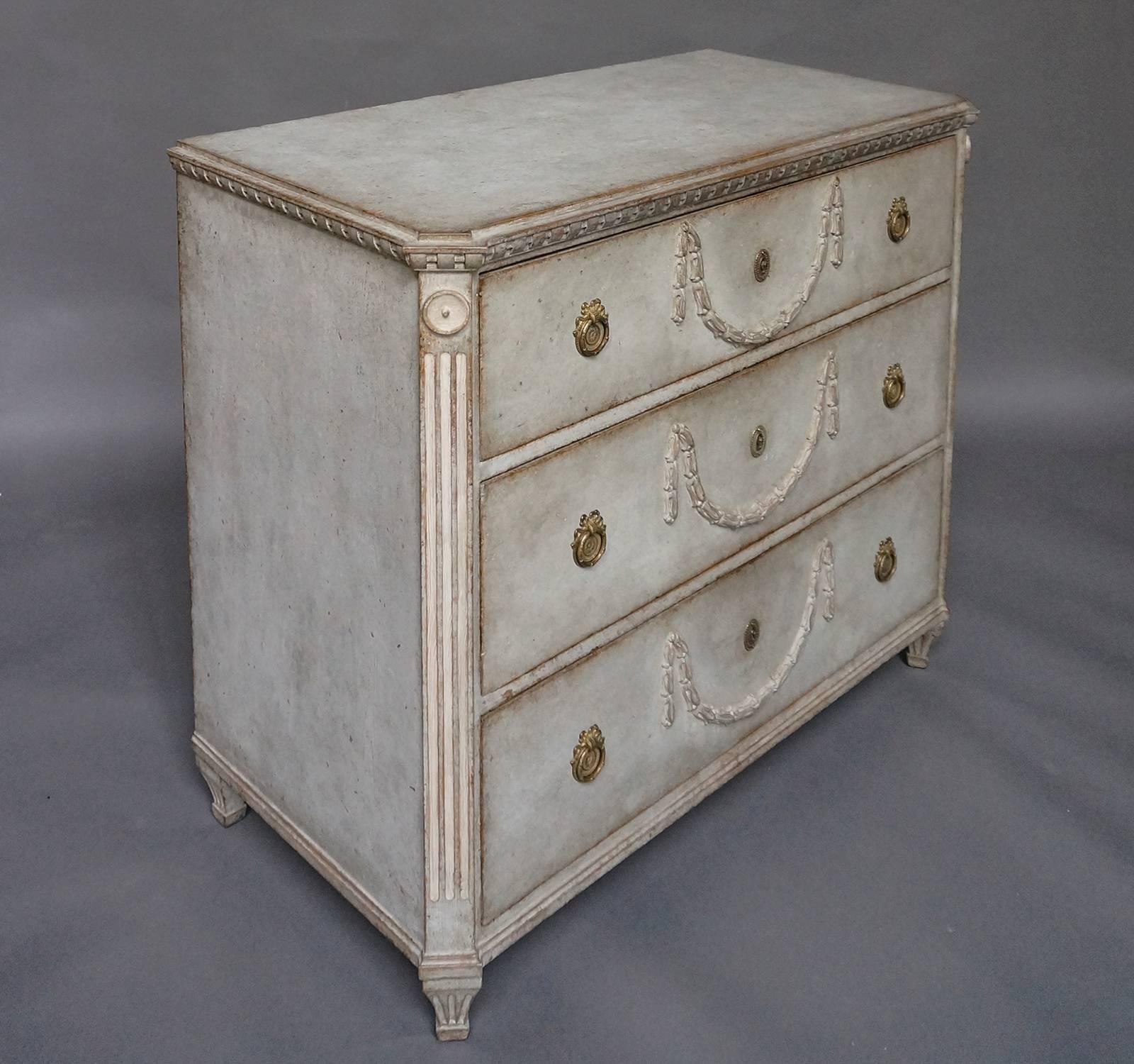 Neoclassical chest of drawers, Sweden, circa 1860, with applied laurel swags on the three-drawer fronts. Reeded corner posts and rod and ribbon carving under the shaped top. A truly special piece.