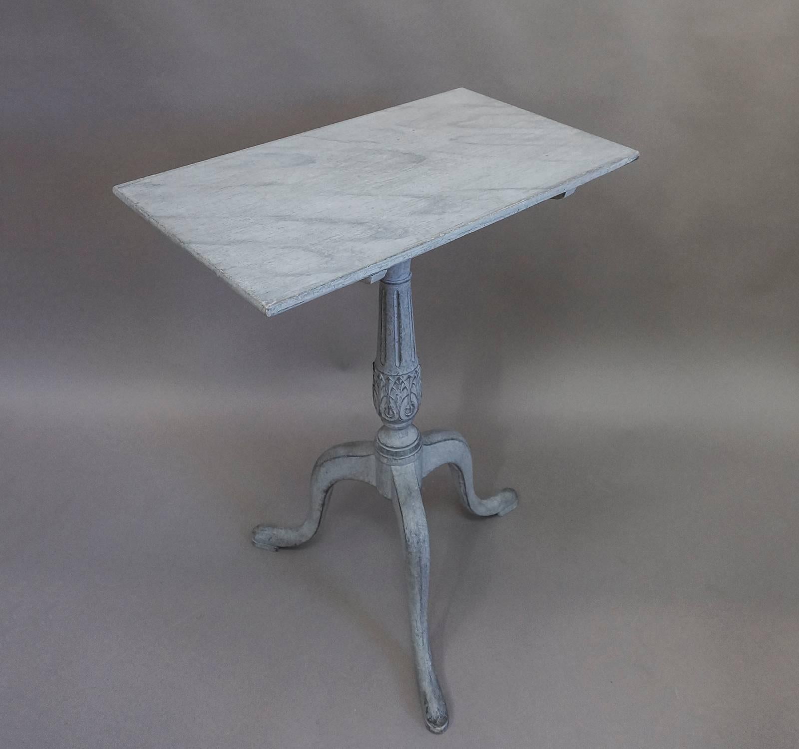 Tilt-top table, Sweden, circa 1820, with acanthus leaf carving circling the pedestal base and three legs with snakeshead feet. The rectangular top is marbleized in shades of blue-gray.