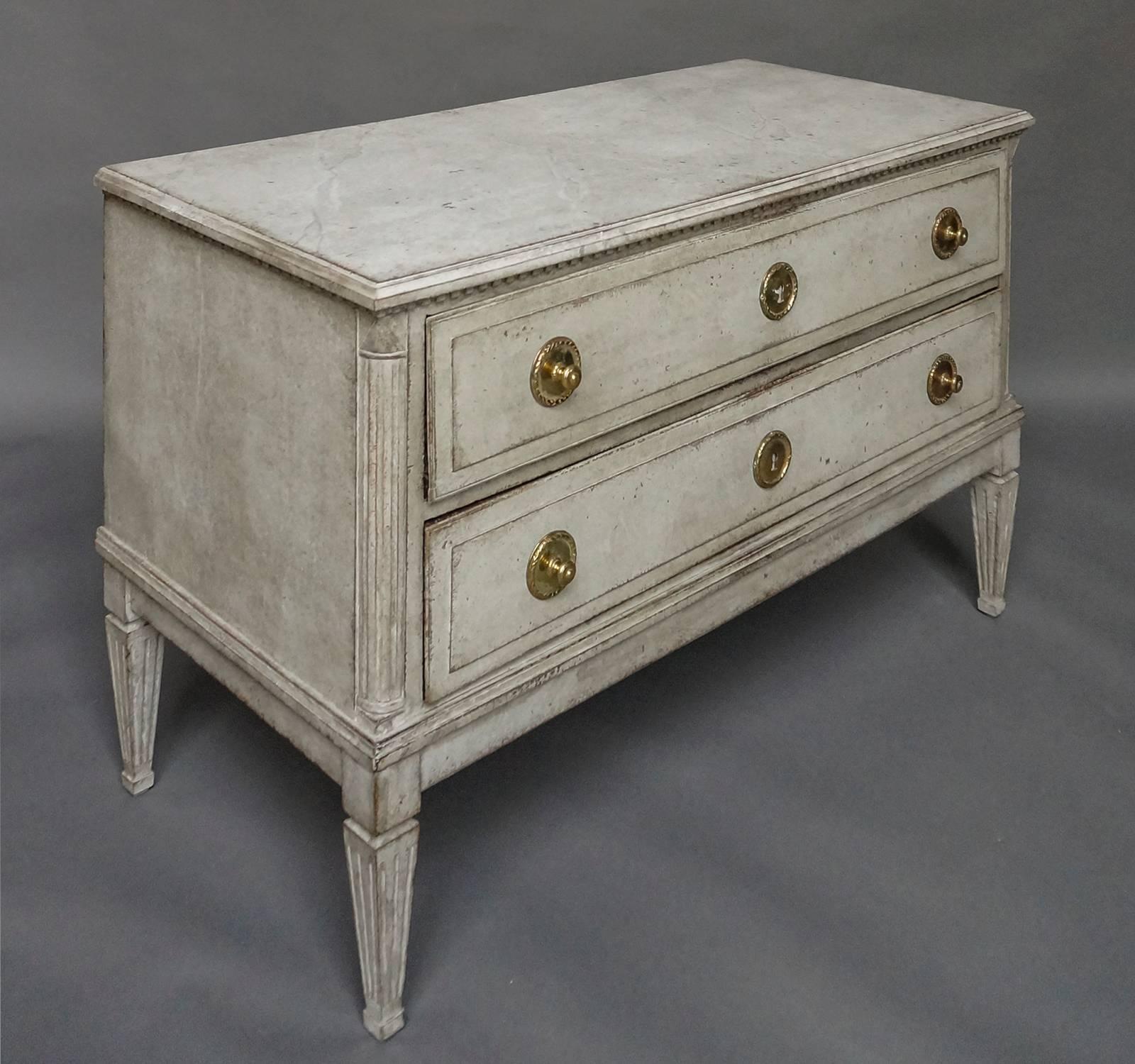 Swedish neoclassical two-drawer chest, circa 1780. Raised panels on the drawer fronts and original brass hardware. Dentil molding under the shaped top, quarter round columns at the front corners and tapering square legs.