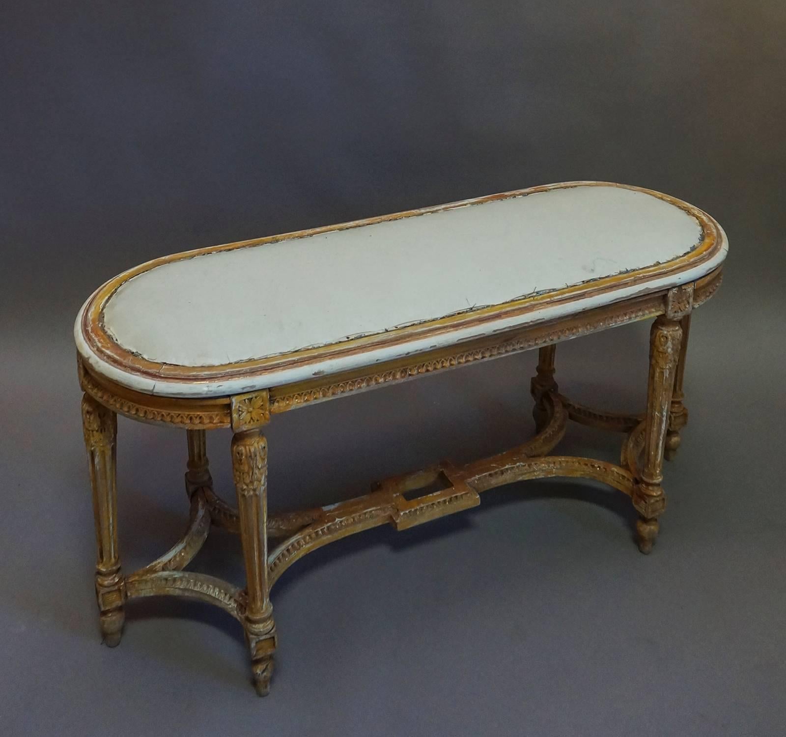Six-legged bench in the Italian Directoire style, circa 1860, which retains traces of its original gilding. Egg and dart molding around the apron and on the stretchers and foliate carving at the top of each tapering round leg.