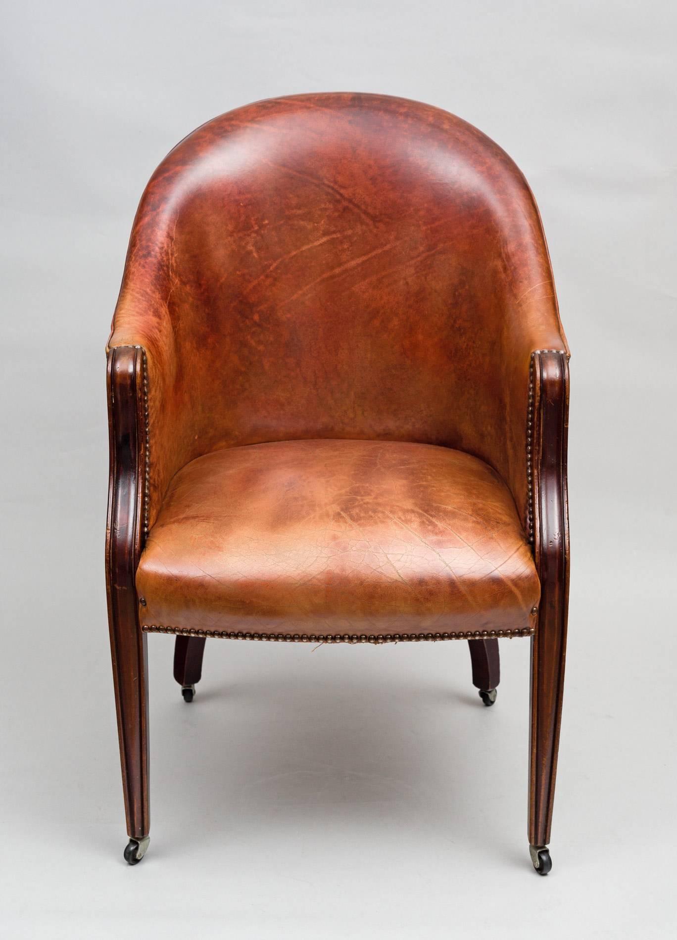 An Edwardian mahogany framed tub chair upholstered in a reddish-brown colored leather with silvered nail heads, a wrap around back with square molded tapering front legs and out-turned back legs on casters.

    

 
 
 
 


