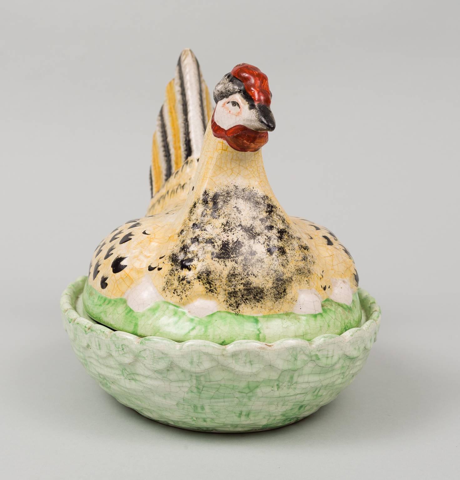 Large Staffordshire hen on nest tureen decorated in striking polychrome glazed colors of pale yellow, black, red and pale green in a crackle ware finish. The hen on her eggs forms the cover and the green basket forms the dish. A very elegant hen,