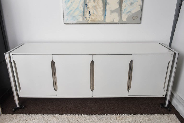 Bring a point-of-view to your room with this 1970s mod dresser. Sculpted white wood doors in white and chrome insert open to six wood drawers. Legs are in aluminum frame detail on each side with white insert laminate. Lacquered this heavy piece will