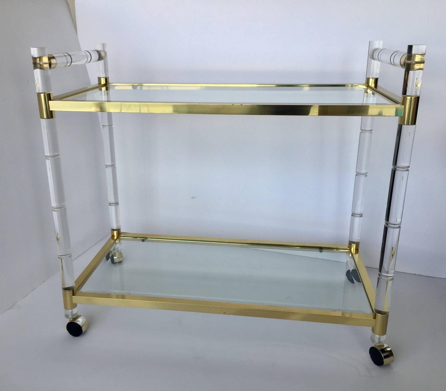 Elegant Lucite and brass bar-cart designed and manufactured very close to the style of Charles Hollis Jones. 
The piece is in great condition and is all original. One glass has a small minor scratch. As the piece is made with real brass, the clear