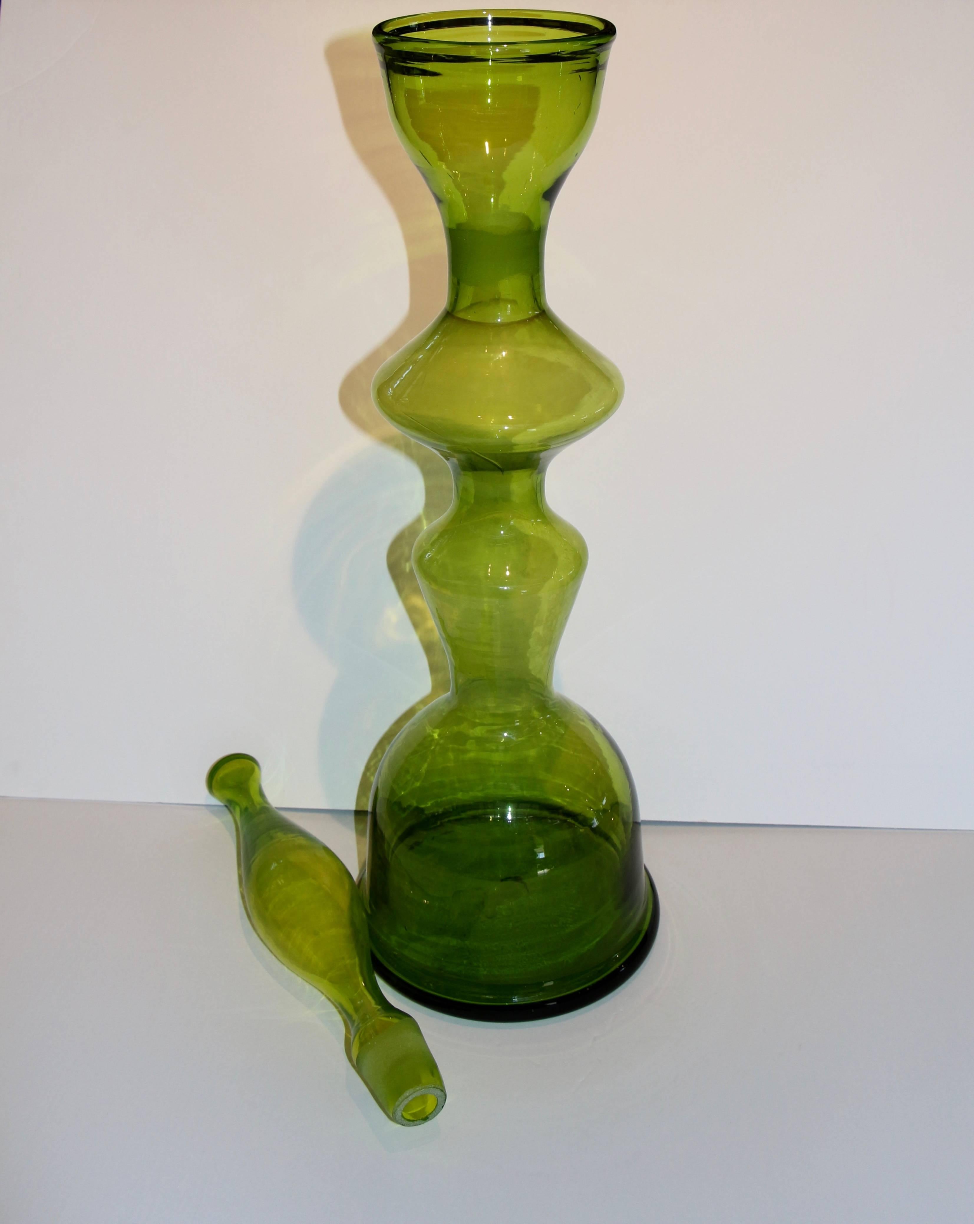 A large greenish decanter designed by Wayne Husted for Blenko. I believe that these were produced in the late 1950s. The stopper and decanter need to be cleaned internally with some soap and water or vinegar.
Please take a moment to visit our art