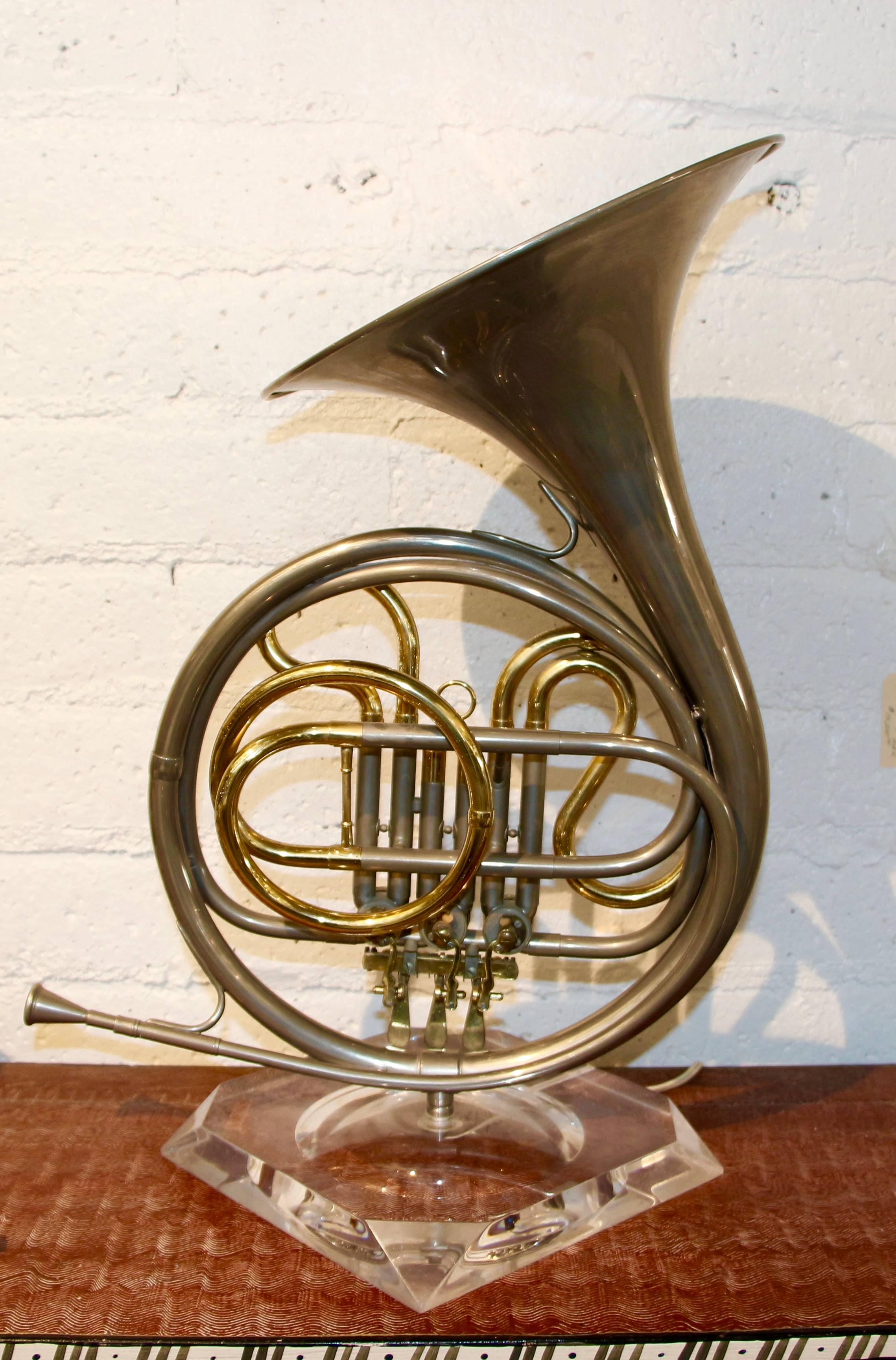 An unusual labelled Carole Stupell collection Lamp made from a French horn mounted on a Lucite base. Original wiring, working. The base has a label. It is a quite unique lamp. Lucite base was a bit scratched so we had it polished. The silver parts