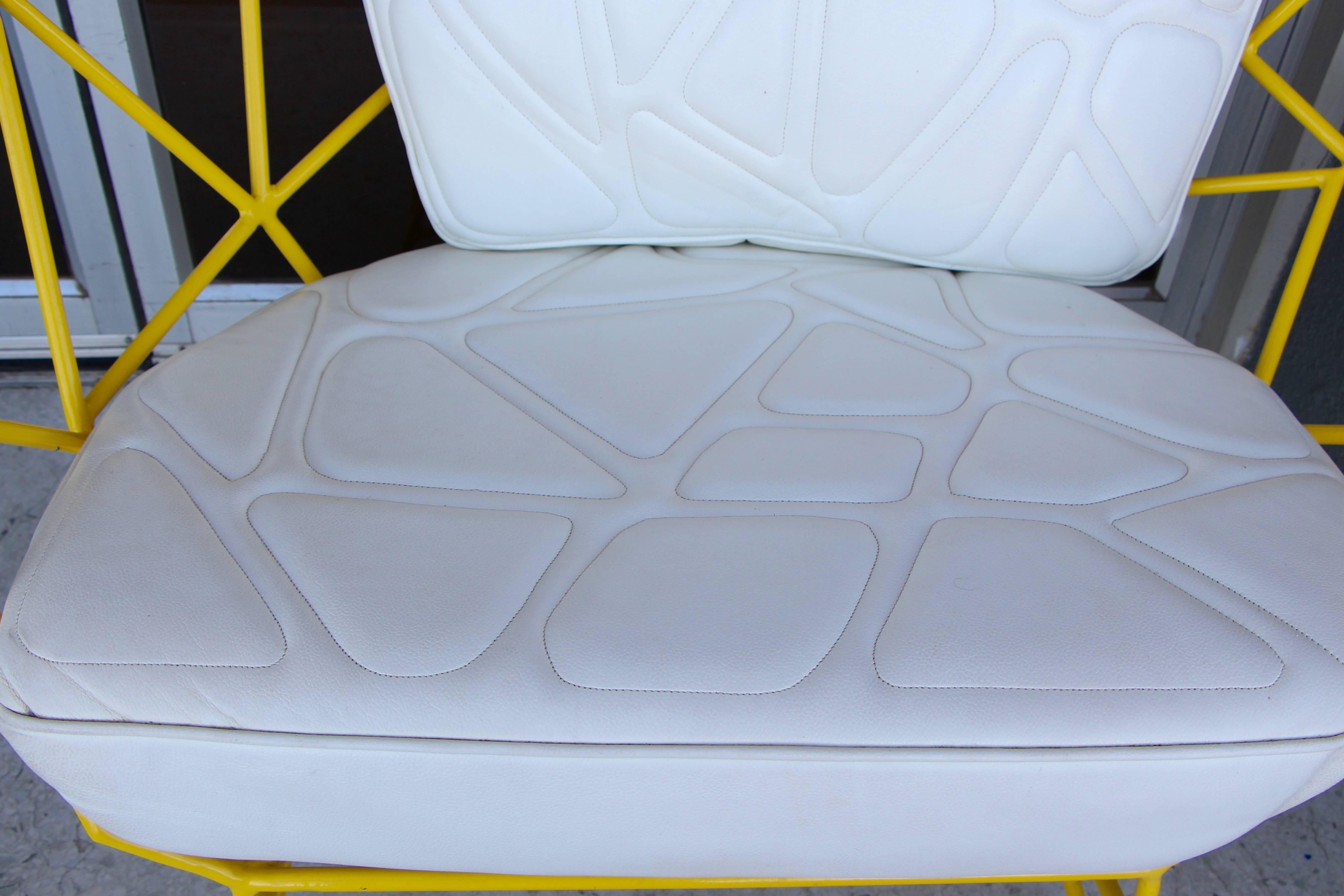A pretty fabulous handmade artisan chair with a most unique stylized stitched geometric cushions. The chair is powder coated in a lovely yellow color. The leather cushions are in good condition, although they show some wear from use and age. A mate