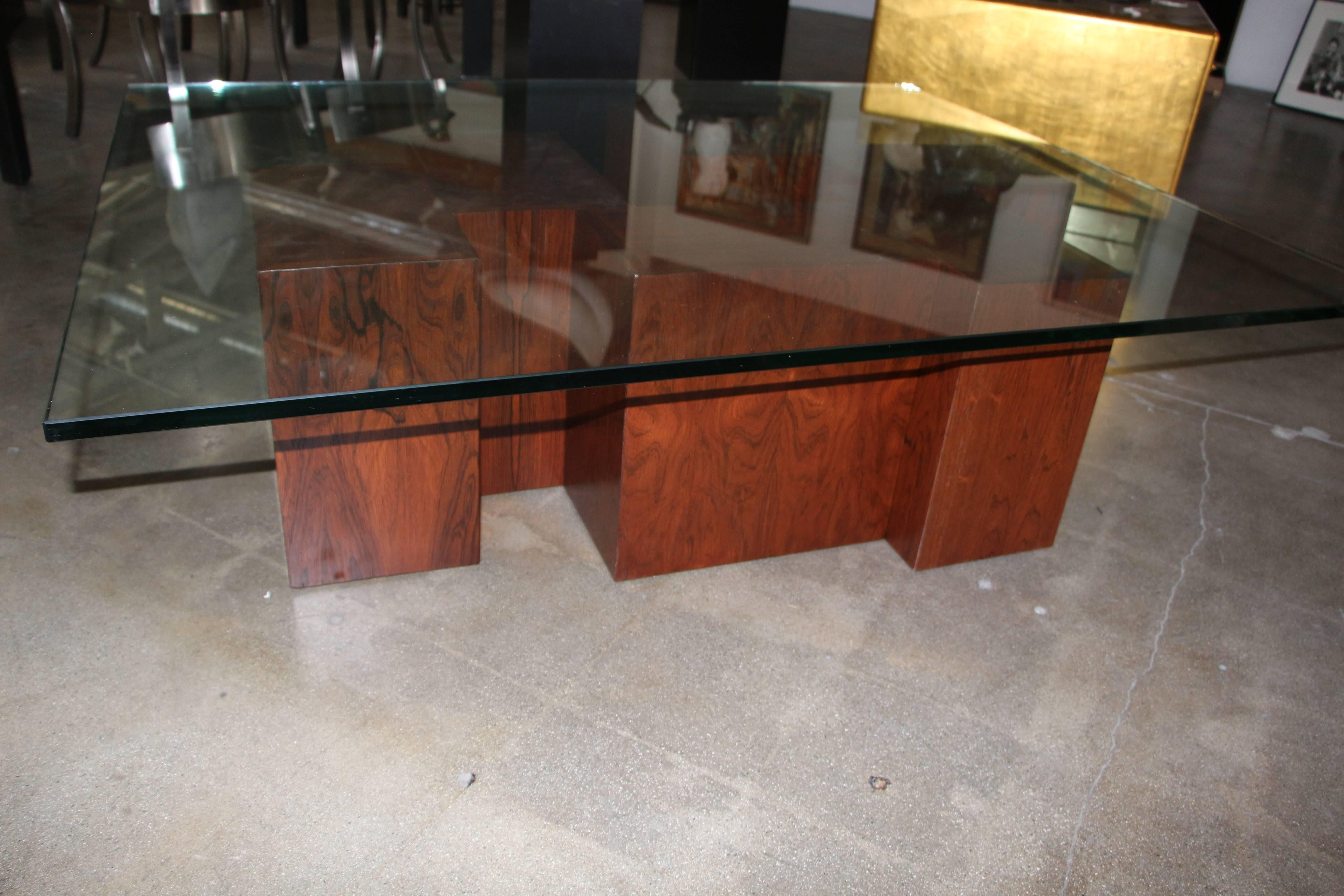 This stunning coffee table consists of rosewood veneered cubes the are fastened together. The rosewood veneer is beautifully grained. Glass top is heavy and in good condition, with minor scratches from age and use. The base has been refinished. This