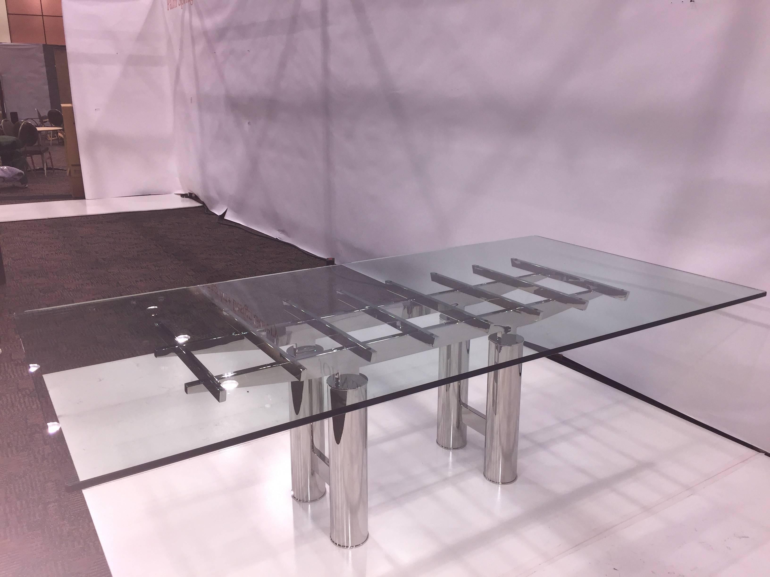 A stunning mirror finish stainless steel Brueton dining table from the 1980s. The glass top measures approximately 48 x 95.75 inches and is in good condition with some minor surface scratches. A visually striking design. The steel finish is in good
