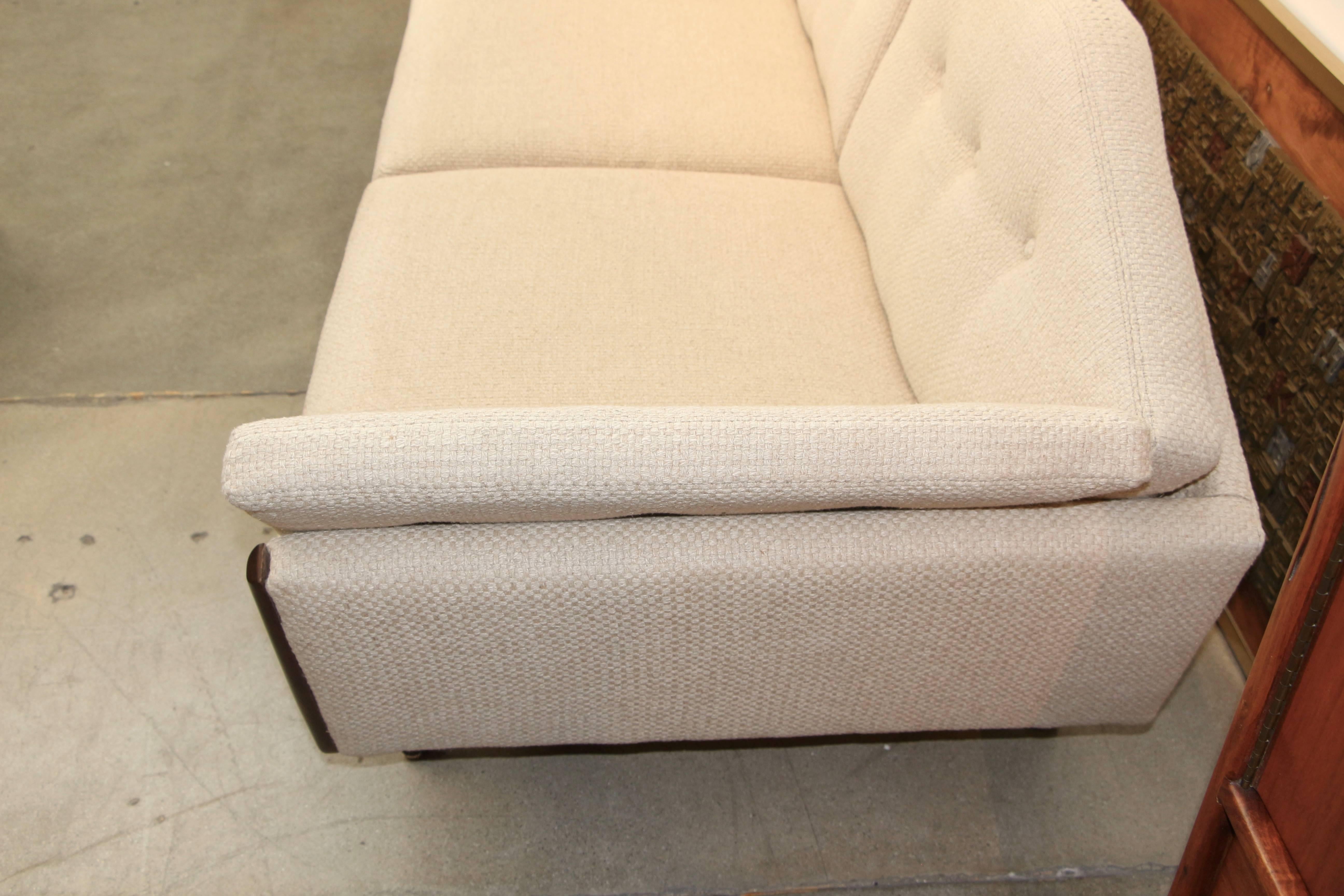 An elegant angled walnut trimmed sofa. We bought and believe it has recently been re-upholstered in a wool weave fabric. There are a couple of spots, the worst of which is pictured. The walnut front has some areas that have been touched up.
Please
