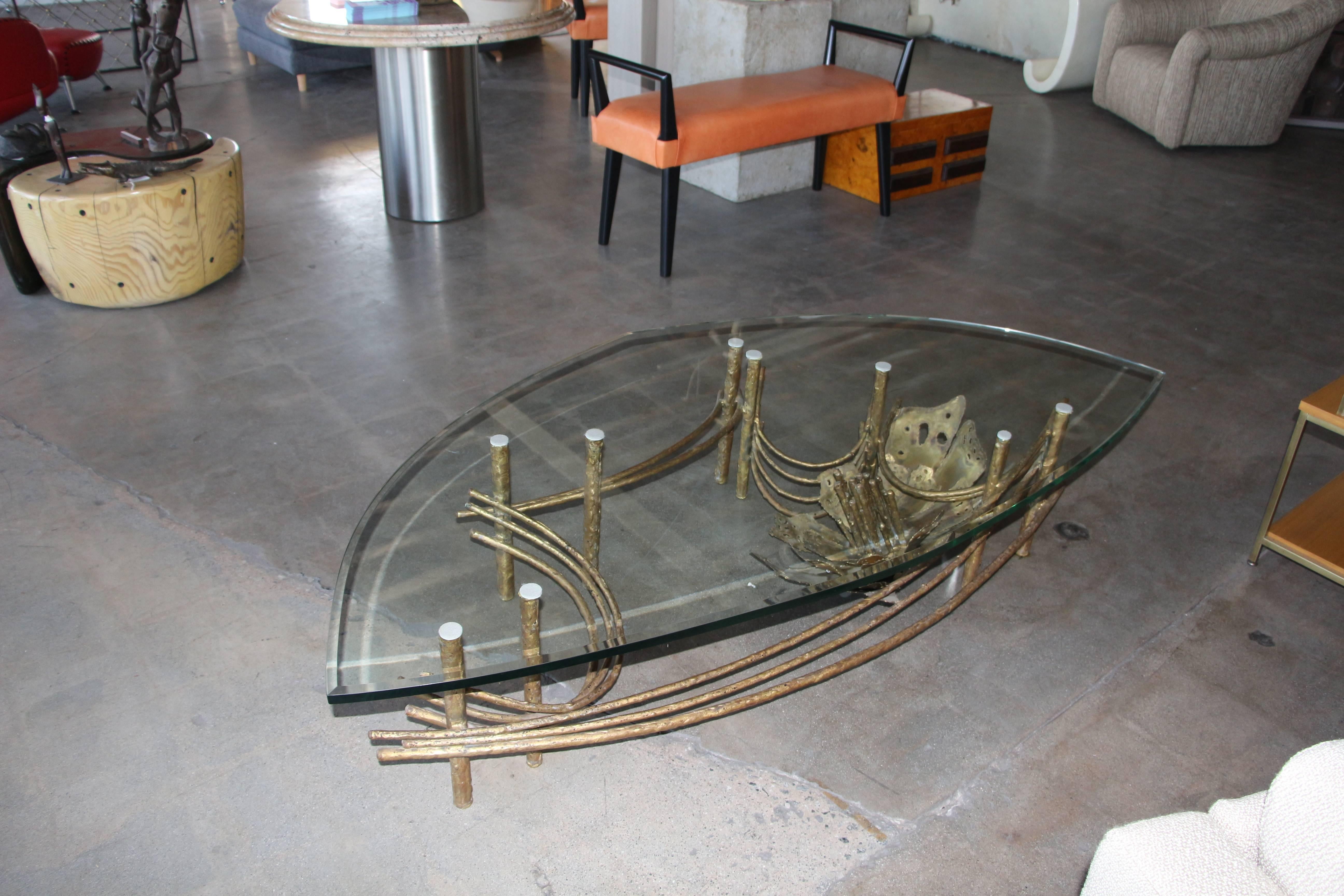 A nice Daniel Gluck coffee table with a most unusual 3/4 inch bevelled edge glass top. The lotus flower design is surrounded by nine supports. It can probably handle a larger top if necessary. The petals of the lotus flower are not all welded to the