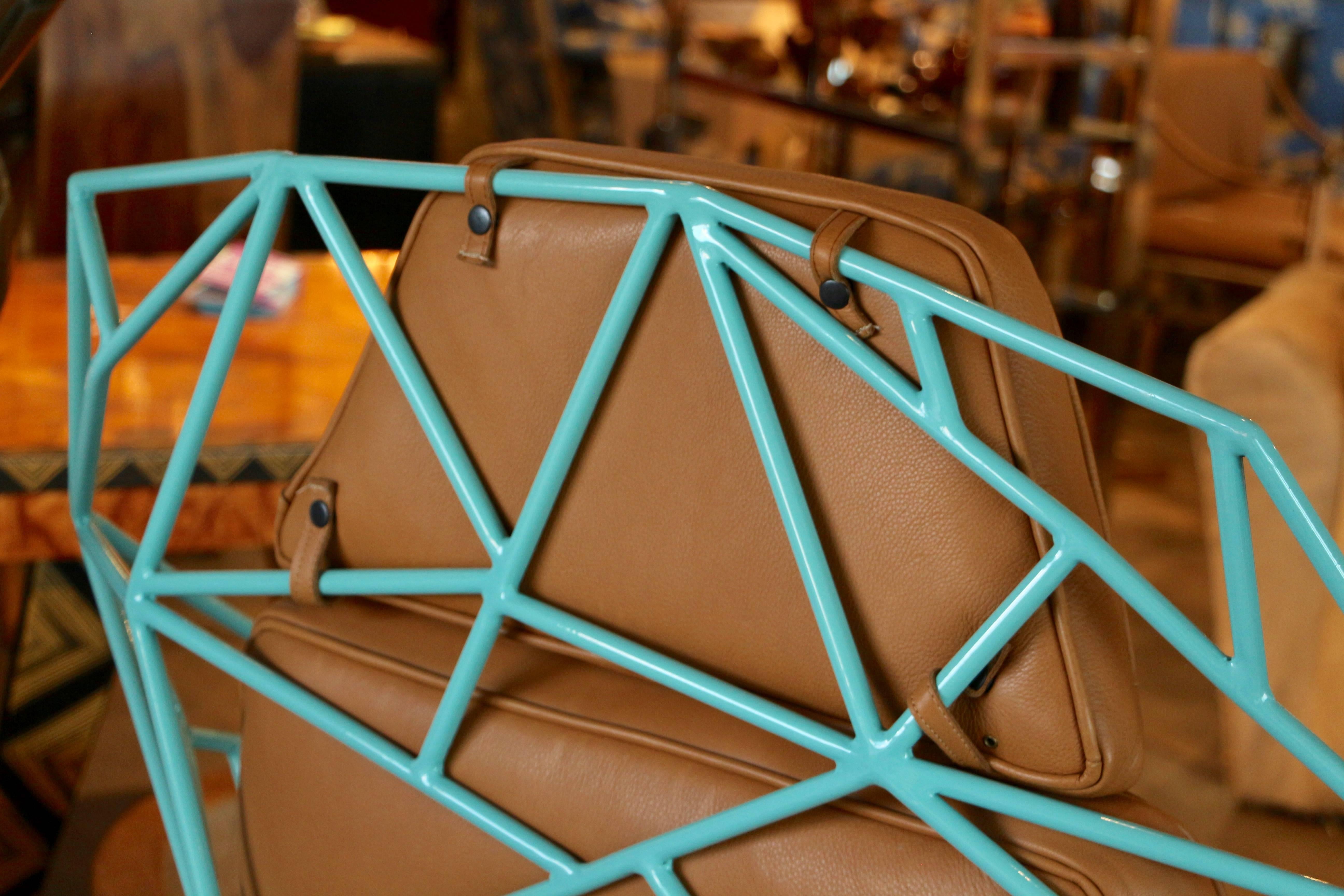 A pretty fabulous handmade artisan chair with a most unique stylized stitched geometric cushions. The chair is powder coated in a lovely turquoise color. The leather cushions are in good condition, although they show some wear from use and age. The