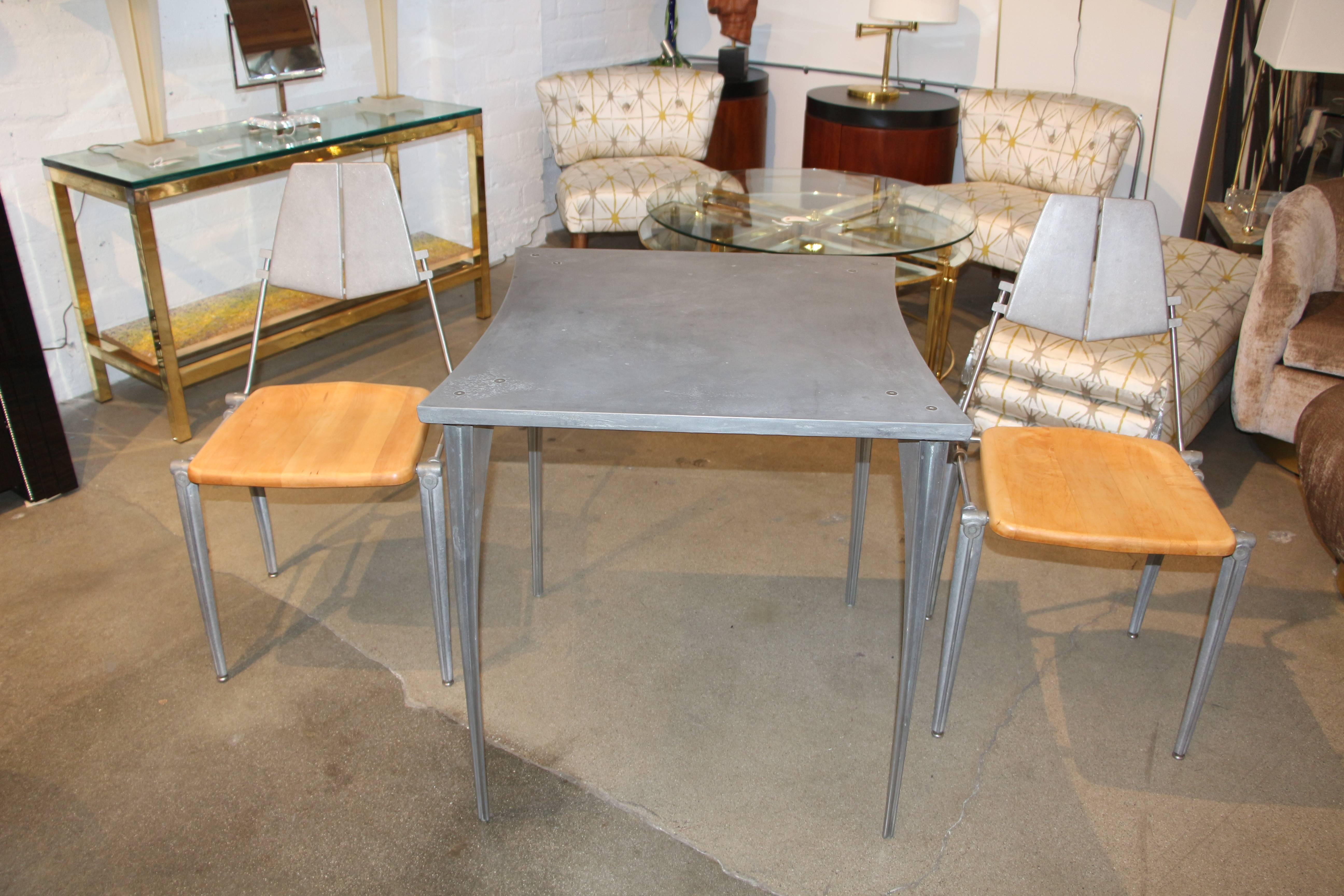 A beautiful cafe table and set of chairs made of aluminum with maple seats. They feature his signature styling. The top of the table is brushed aluminum and the legs are polished. The legs are polished. Chair measurements are 20 D, 18.5 W and 34.5