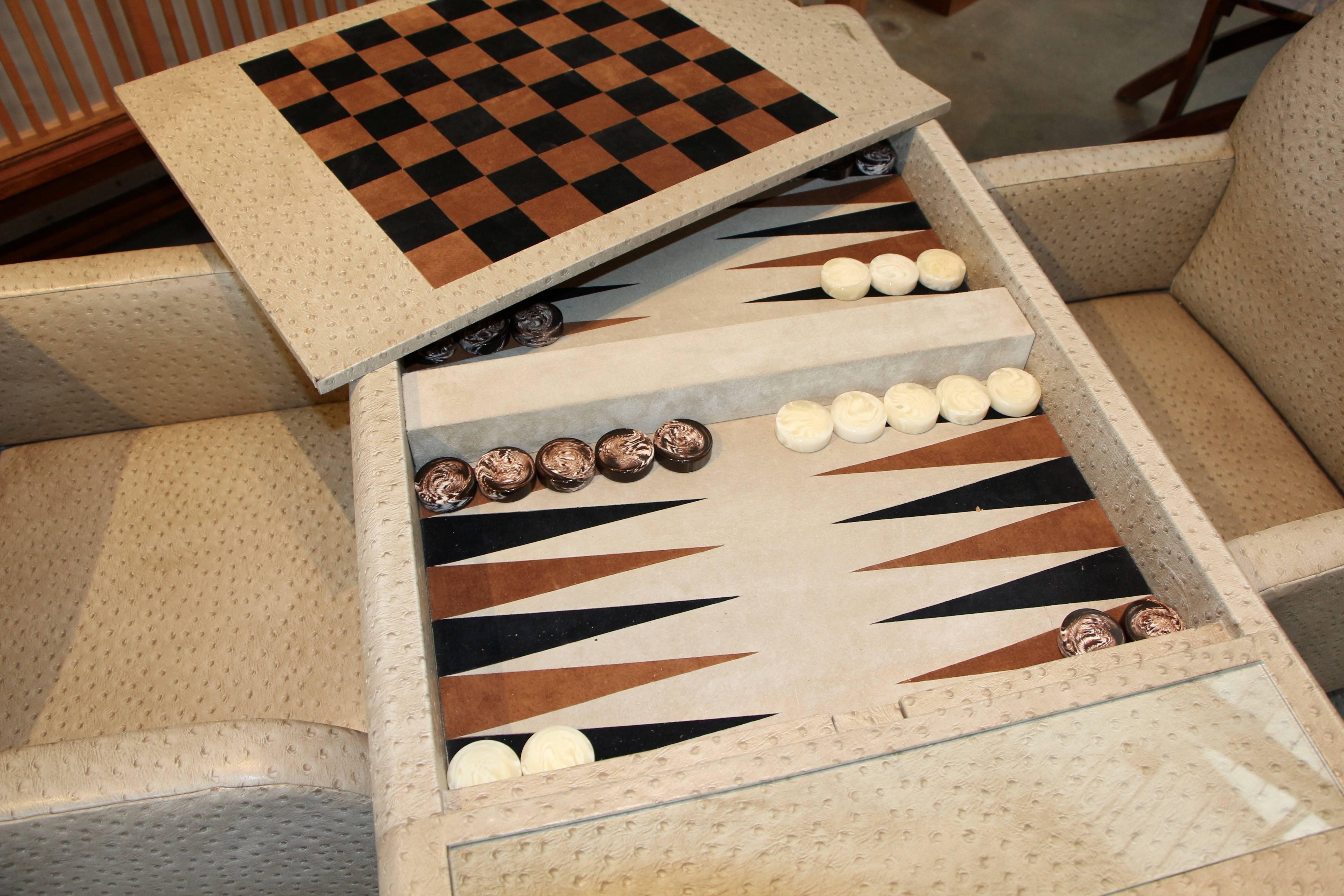 A nice faux ostrich covered game table with matching chairs. We believe the material to be faux ostrich vinyl. The top flips over to reveal a chess board and below in the well is a backgammon board with pieces. The top is lifted up by a clever
