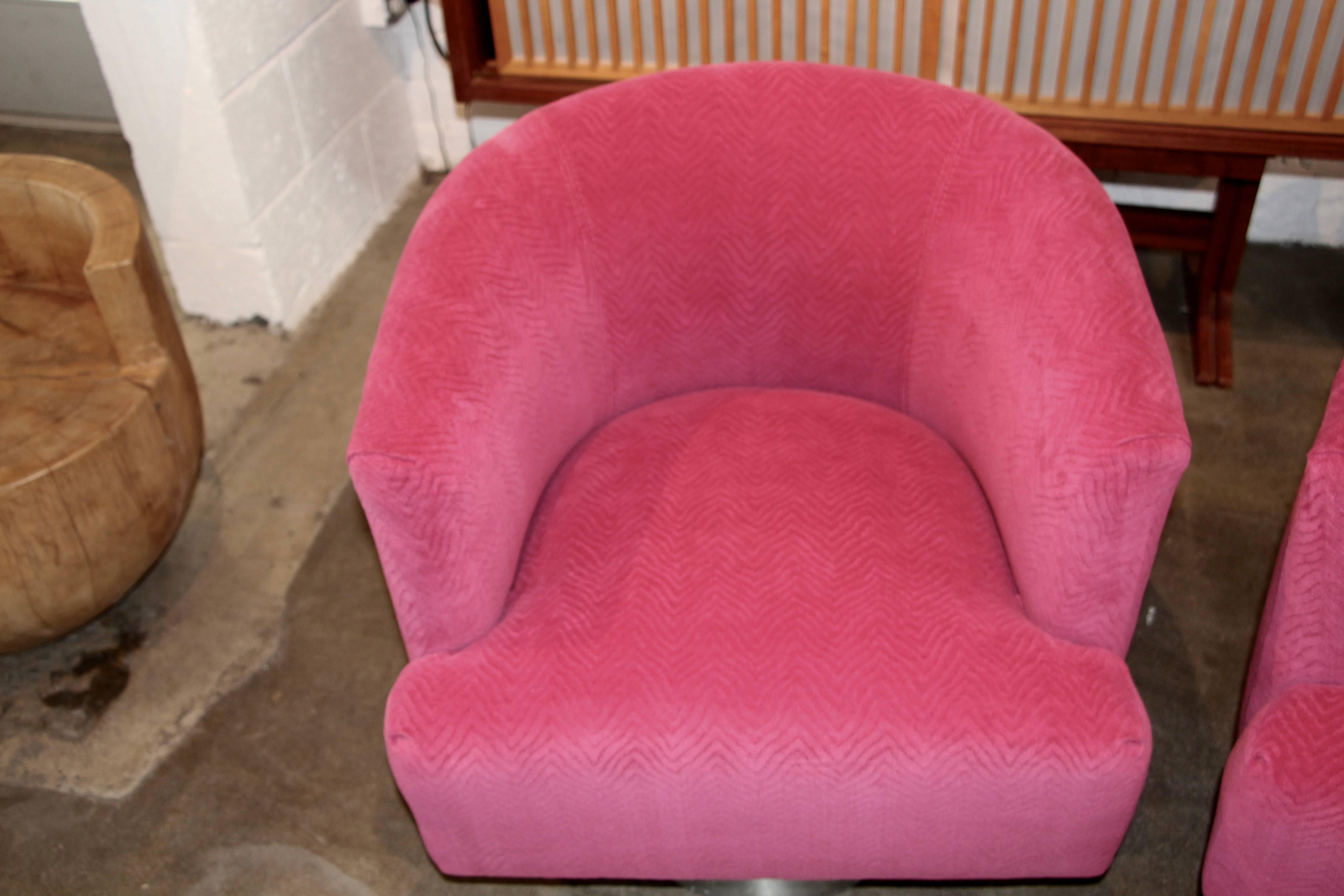 A nice elegant pair of swivel chairs on raised steel clad vases. These chairs have been re-upholstered in a vintage fuschia wool velvet with a slight pattern the upholstery job is good. There are numerous dings to the bases. Please see the detailed