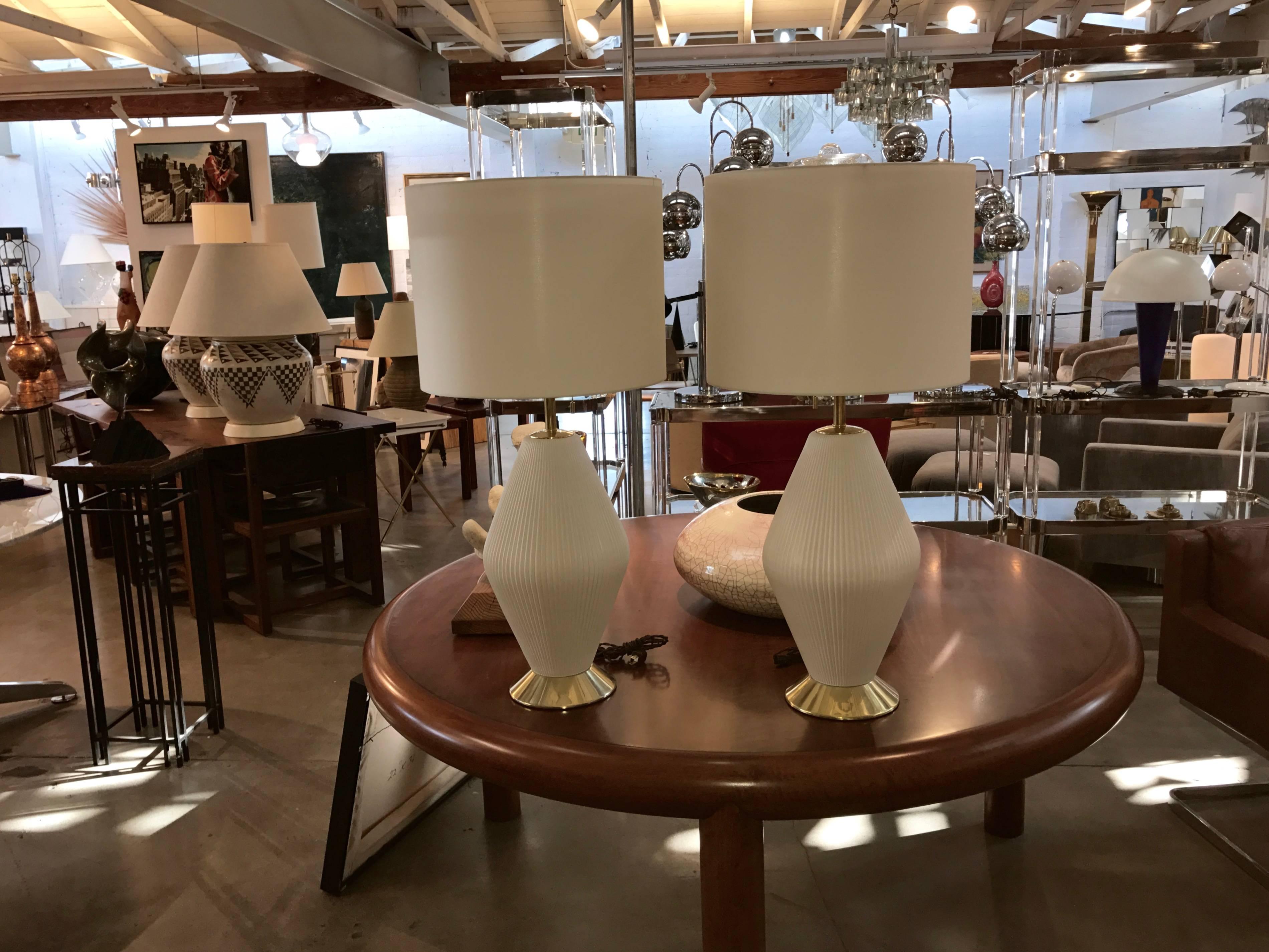 A beautiful pair of restored porcelain and brass designed by Gerald Thurston for Lightolier, we believe in the mid-1950s. These have been restored and rewired. A really spectacular pair of lamps. the lamps are much closer to white/cream. 