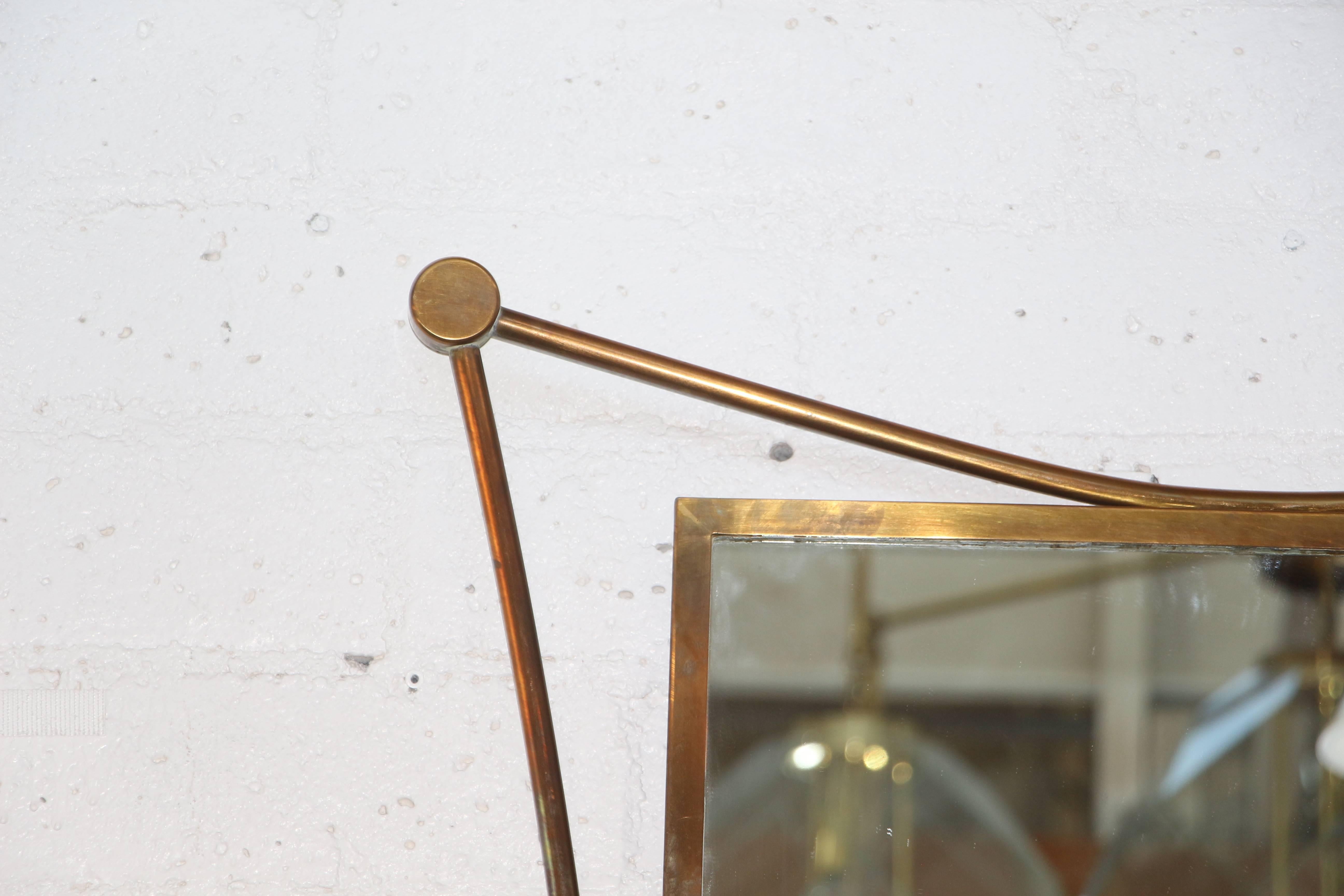 A highly Stylized brass mirror likely from the 1950's in the manner of Ico Parisi or possible even Gio Ponti. The wood back which is pictured shows it's age. Some of the screws have been replaced. The Mirror is in age appropriate condition, with