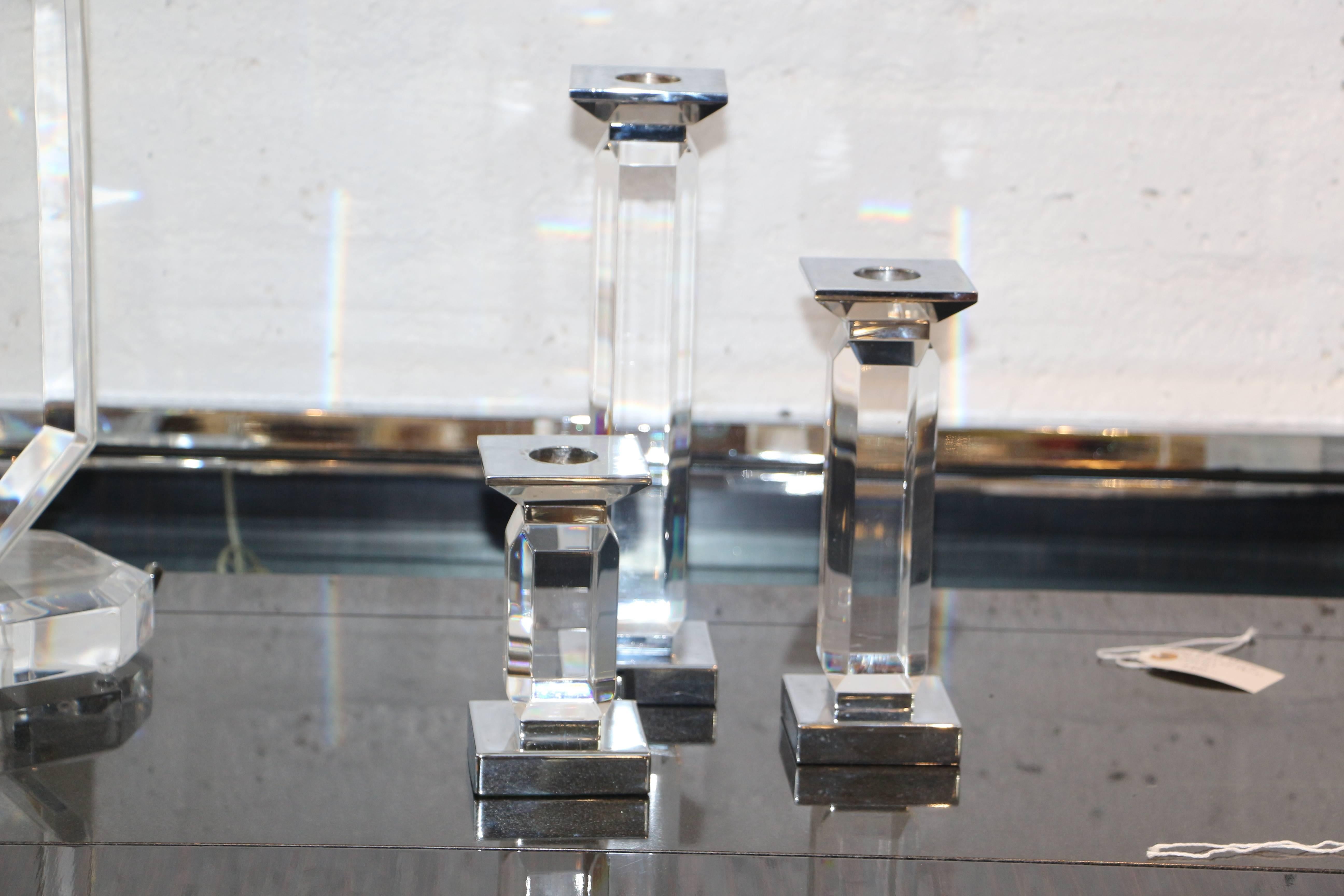 A trio of staggered height candlesticks in Lucite and nickel. The Lucite is faceted. The heights are as follows 12.9 and 6 inches tall and they are 3 x 3 inches. They are in good age appropriate condition with minor nicks, scratches and wax residue.