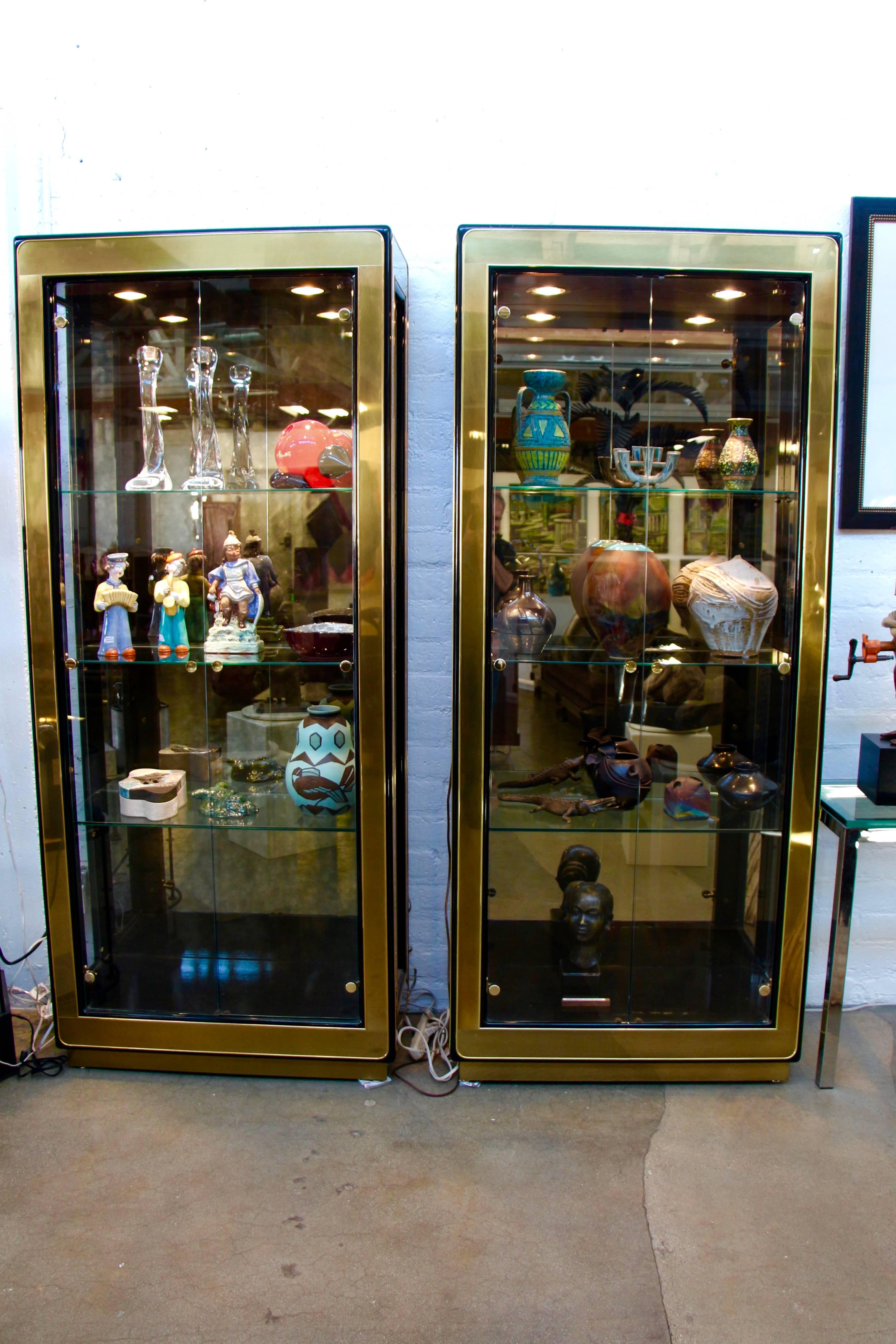 A very nice pair of Mastercraft display cabinets or vitrines in brass and glass. Each still has the original label. These are very clean cabinets with the exception of the black bases which have scathes and nicks and some missing paint, the worst