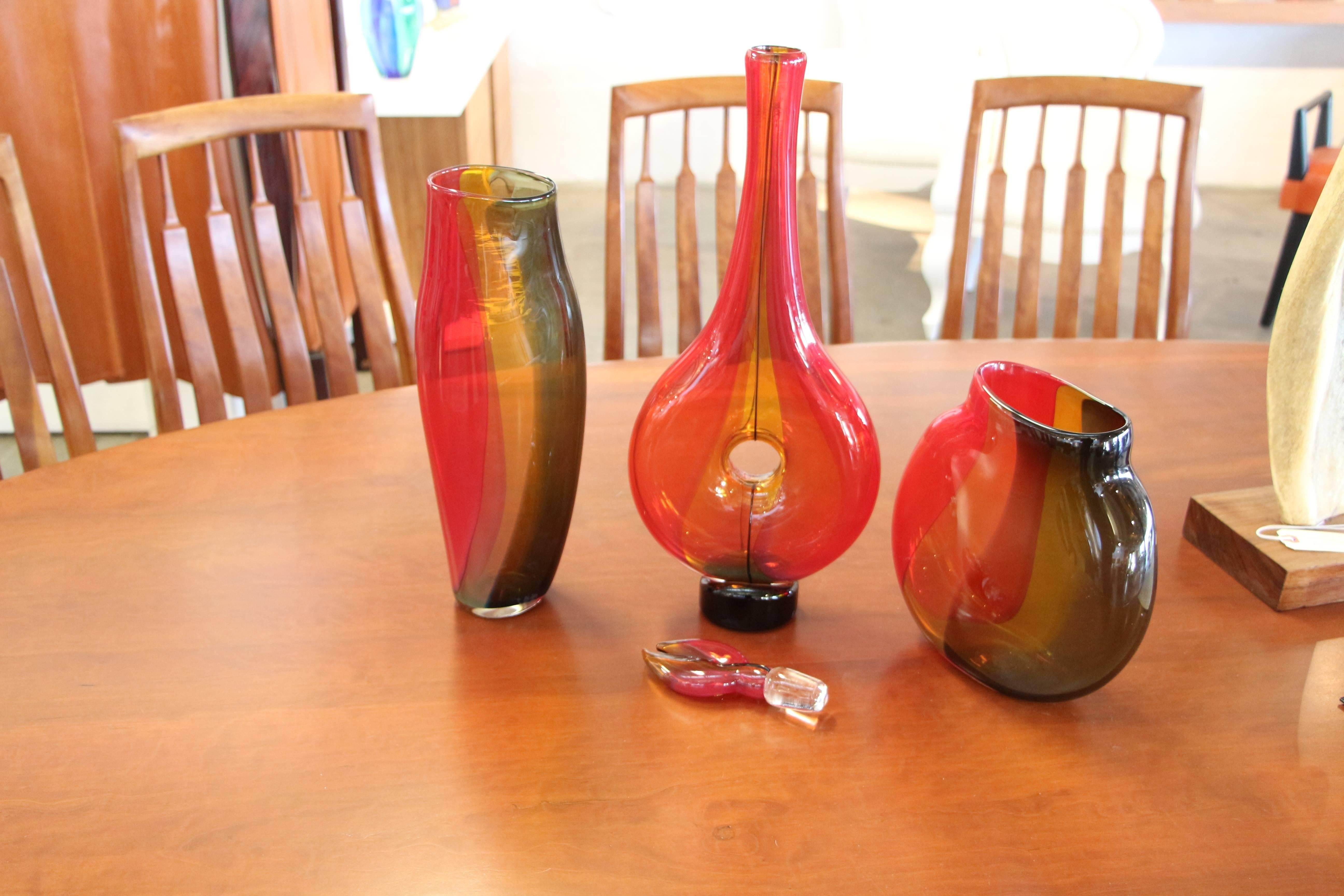 Beautiful signed pieces of glass. I cannot make out the signature, which is the same on all three. They are all dated 2005. The decanter has almost a lobster claw shaped handle. Very nice color and all are in great condition. The tallest decanter in
