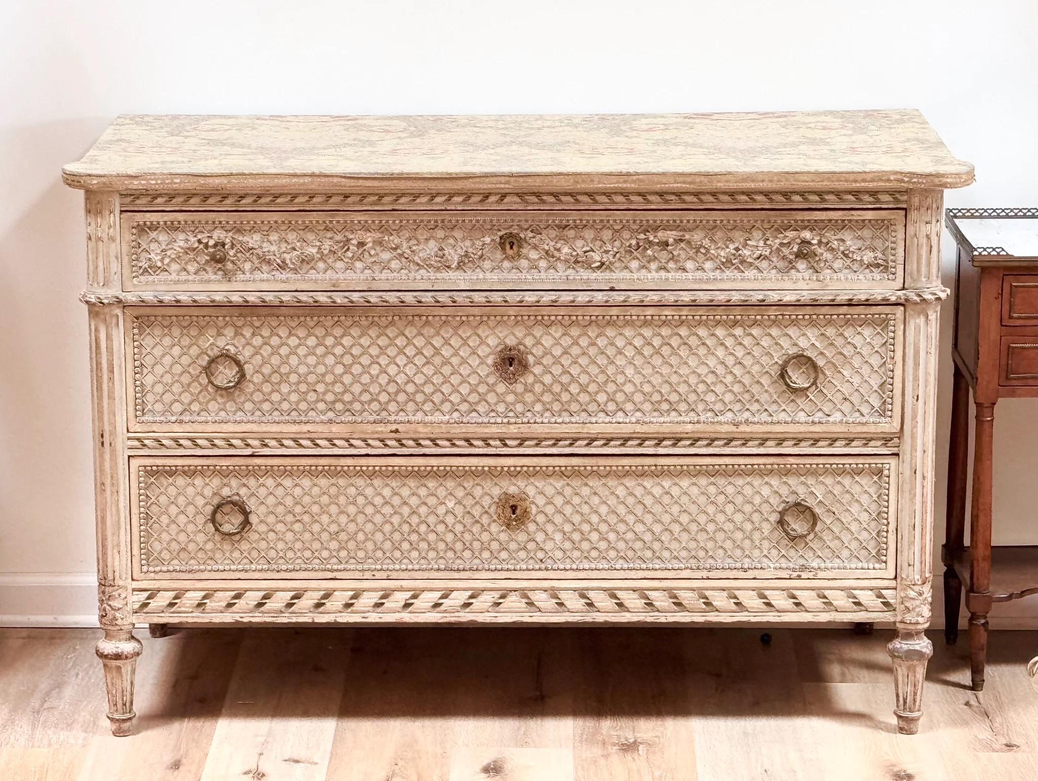 Commode française sculptée et peinte, fin du 19e siècle, style Louis XVI. Le plateau rectangulaire avec un damas de soie floral appliqué plus tard au-dessus d'un boîtier conforme équipé de trois tiroirs gradués sculptés en treillis, le tiroir en