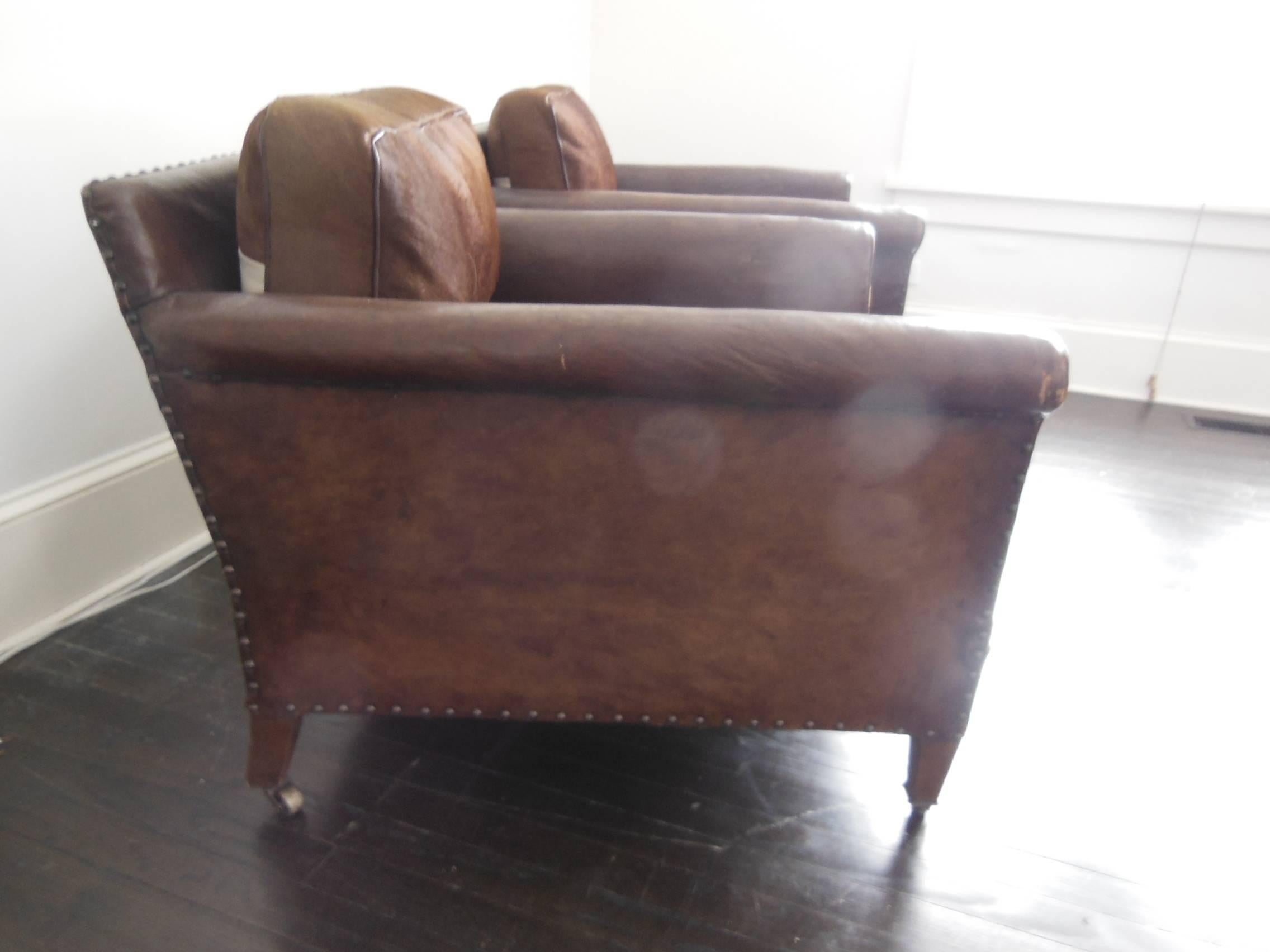 Beautiful pair of French leather armchairs with hide cushions very deep seats on casters.