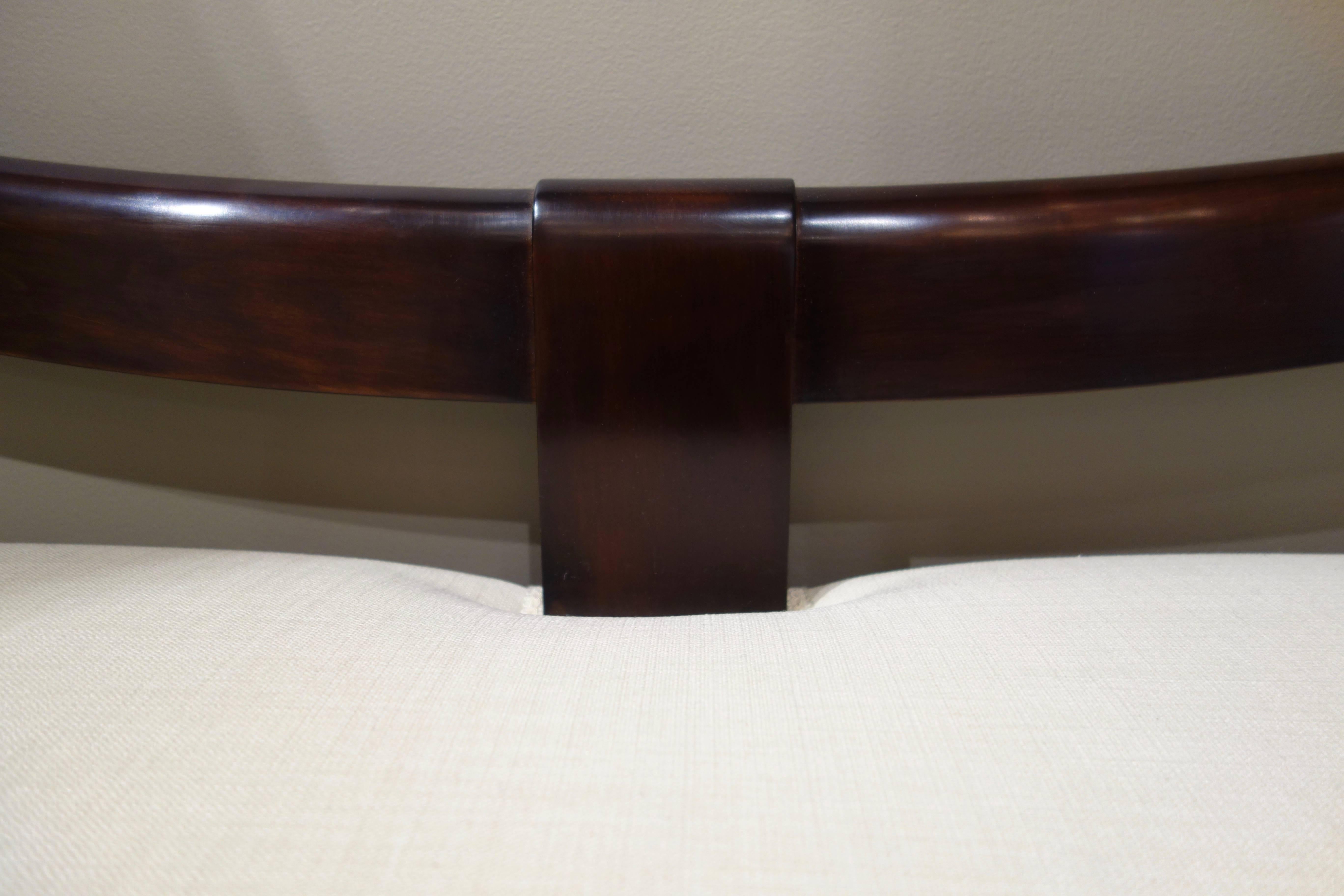 An Italian long bench or settee re-editioned originally designed by Emilio Lancia, the Italian architect and designer who was in partnership with Gio Ponti from 1923-1933. The bench of dark brown mahogany features a curved back with centre