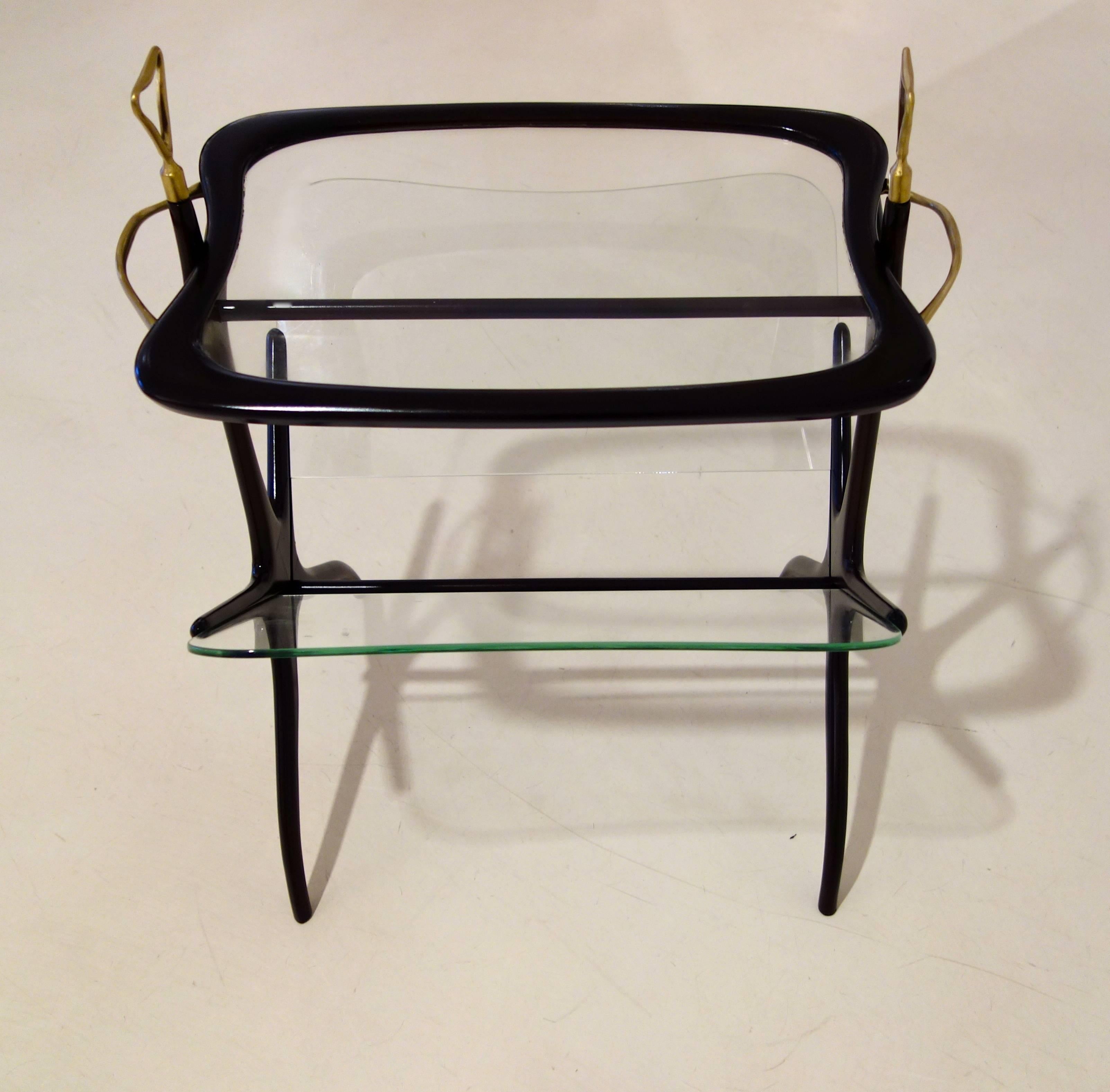 Italian Mid-Century side table featuring a removable tray top resting on a glass sided magazine rack with brass finials and handles.
