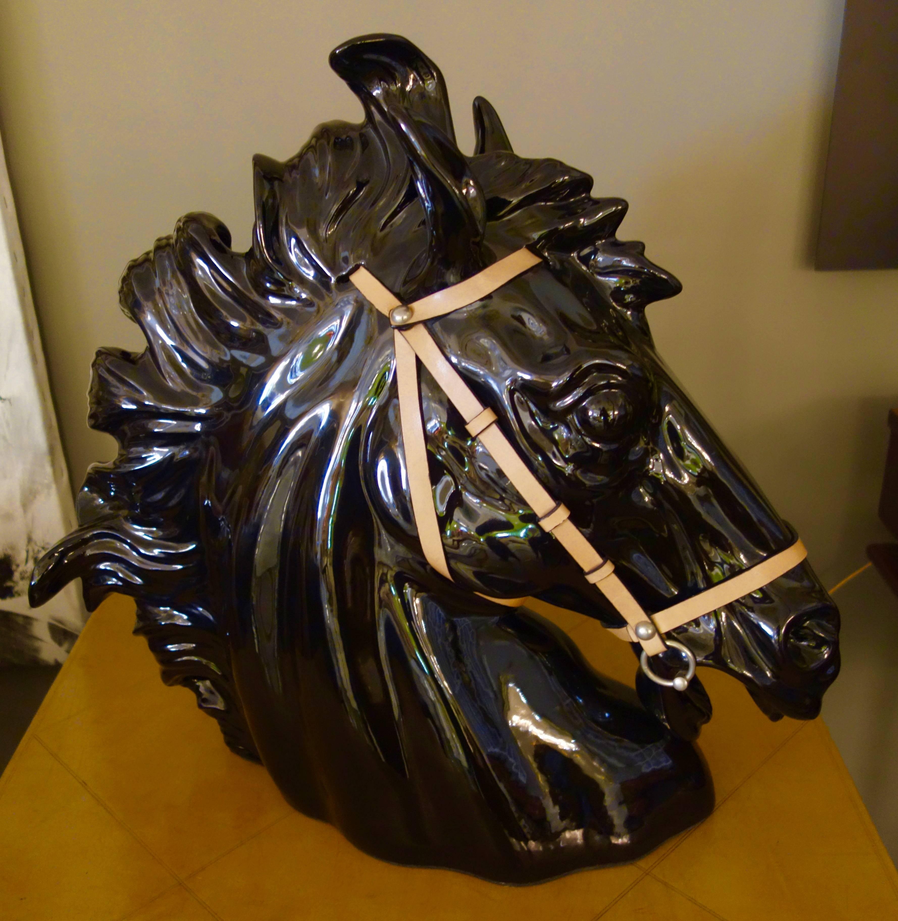 A large dimensional and well-articulated black ceramic horse head sculpture by Gucci with leather bridal and Gucci label affixed to bottom.