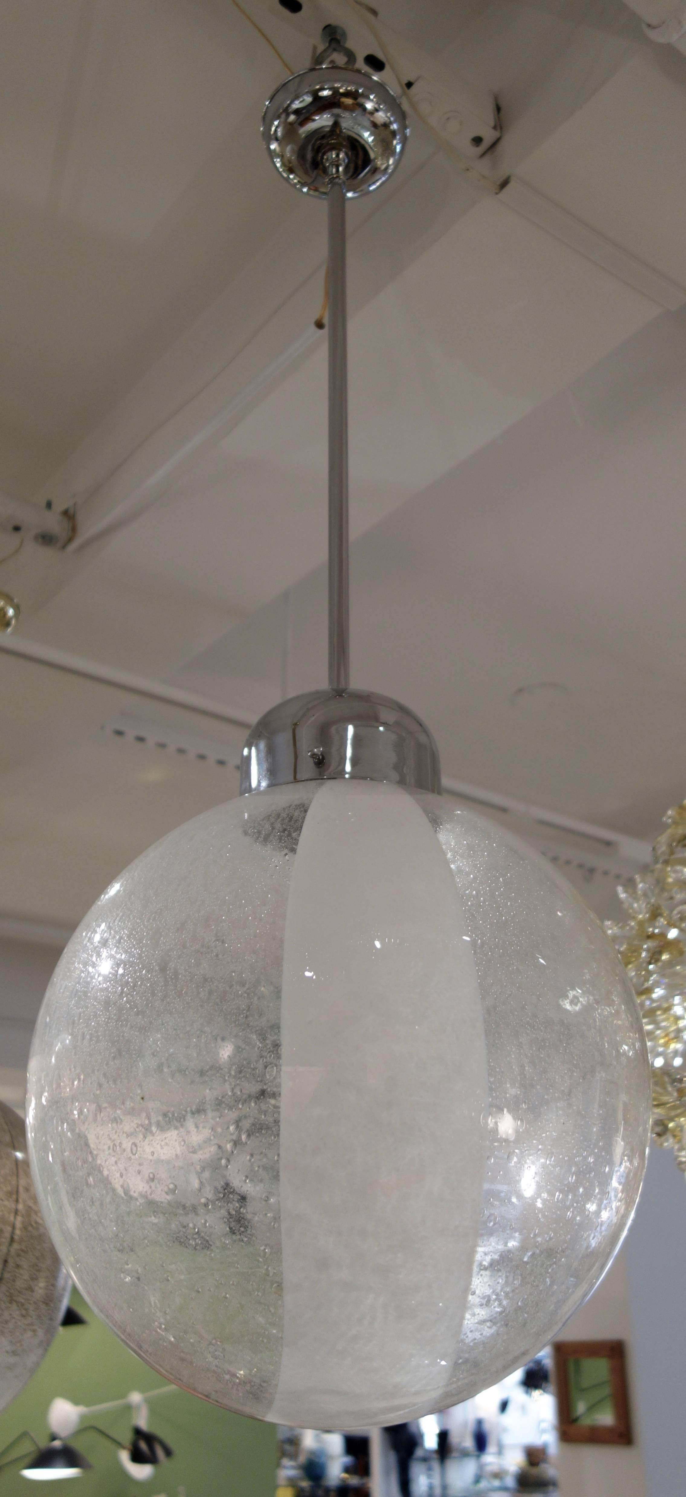 An Italian Mid-Century handblown Murano globe/ pedant/ chandelier comprised of semi-opaque clear glass mottled with infused bubbles with a broad opaque white swirl with chrome pole and canopy, newly wired with a bulb that can accommodate a 100 watt
