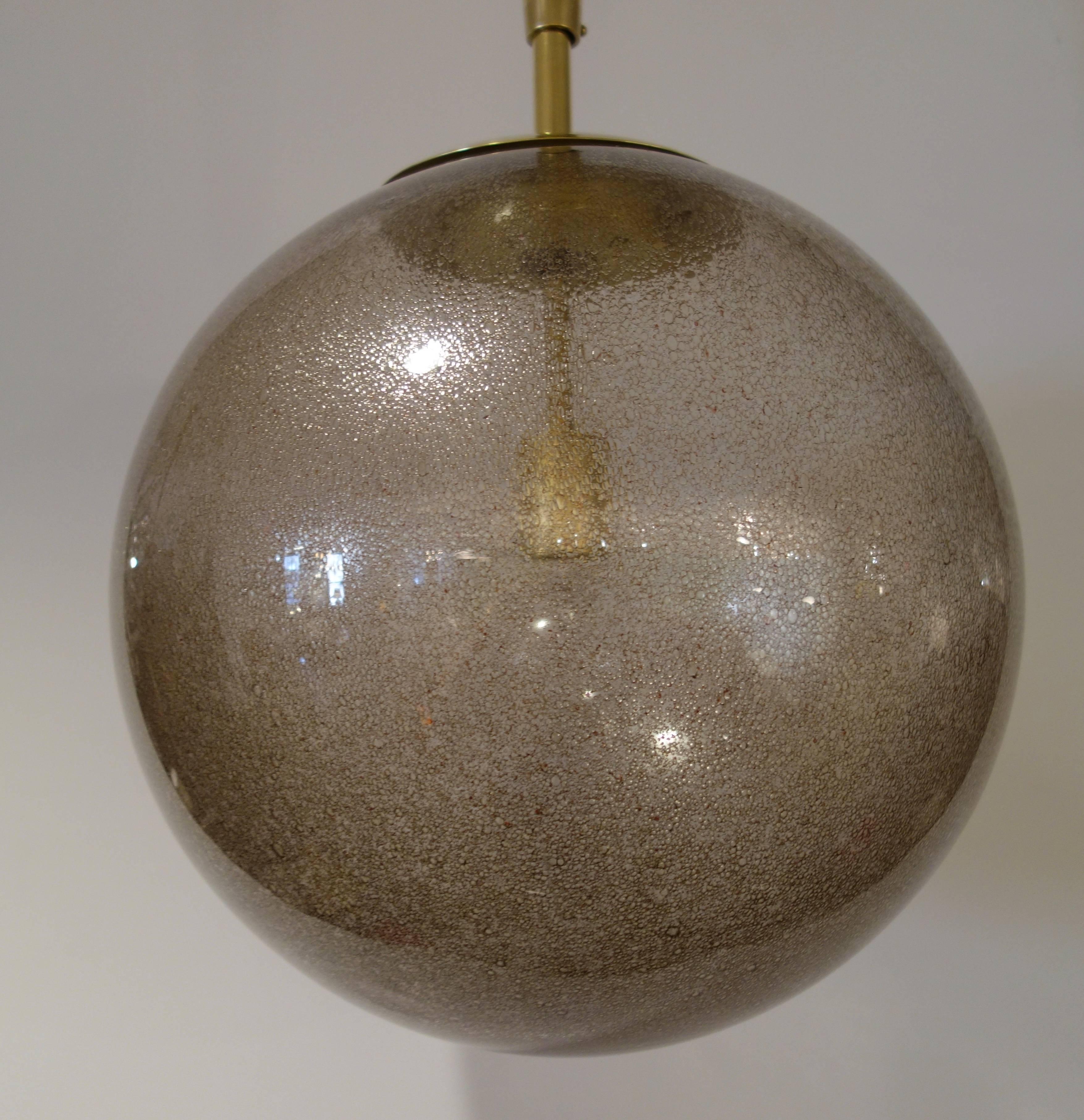 A large Mid-Century globe or chandelier of thick bronze toned handblown Murano glass with all-over small bubbles creating a sparkling effect when lit suspended from a custom conical brass shaft and canopy newly wired for the American market