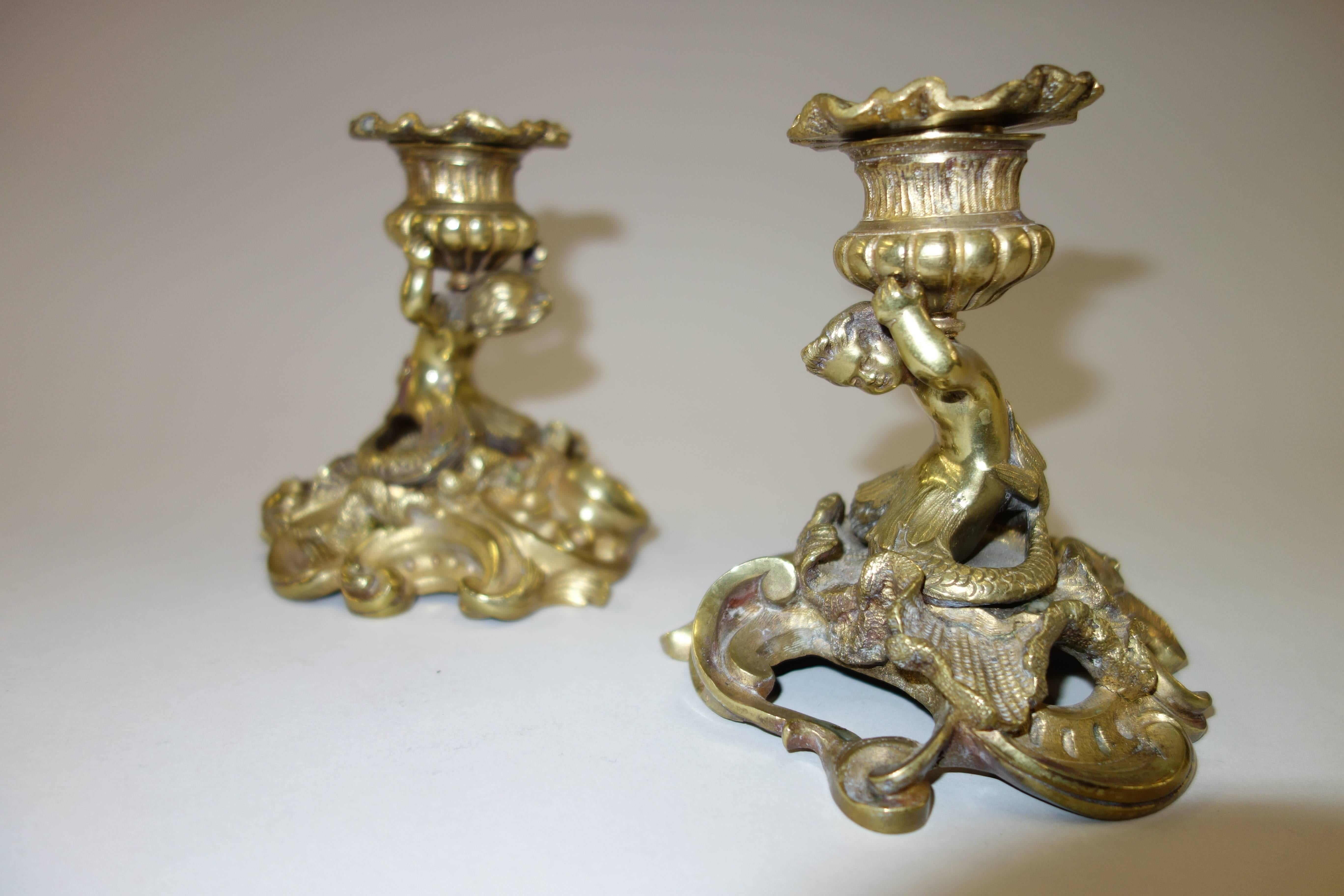 A pair of late 19th century Italian bronze candlesticks or candleholders comprised of mermaids situated on rock-like outcrop, shouldering fluted urn-shaped candleholders, foundry marks on the base.