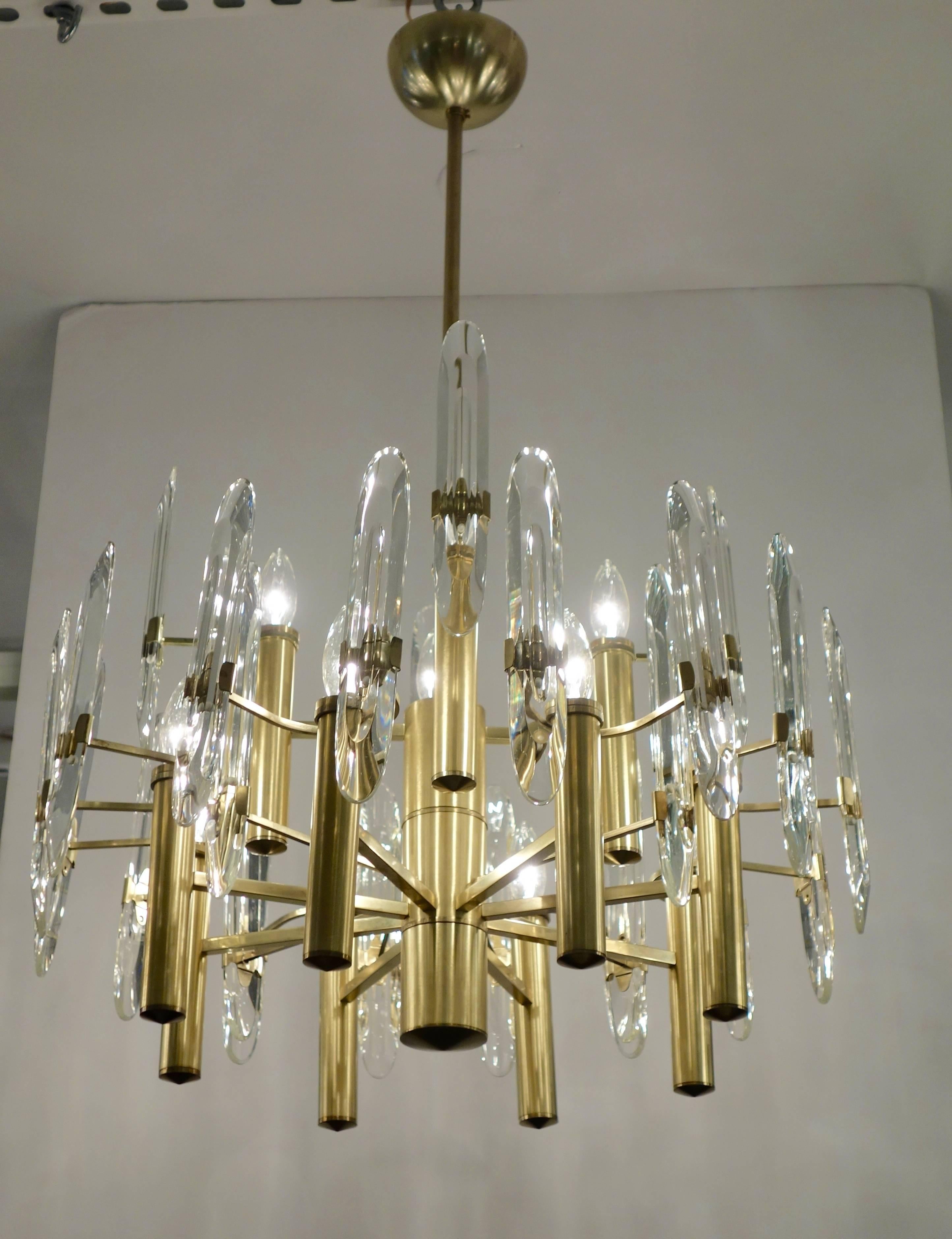 Italian Mid-Century Sciolari chandelier featuring 12 sockets and 24 beveled glass prisms radiating from a central cylinder from multi-levels secured with both double and single arm brackets from the re-plated satin brass frame, rewired for the